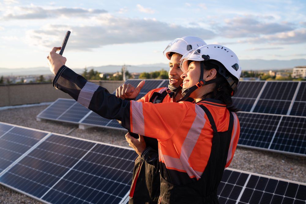 Hispanic workers taking selfie on rooftop solar panel installation