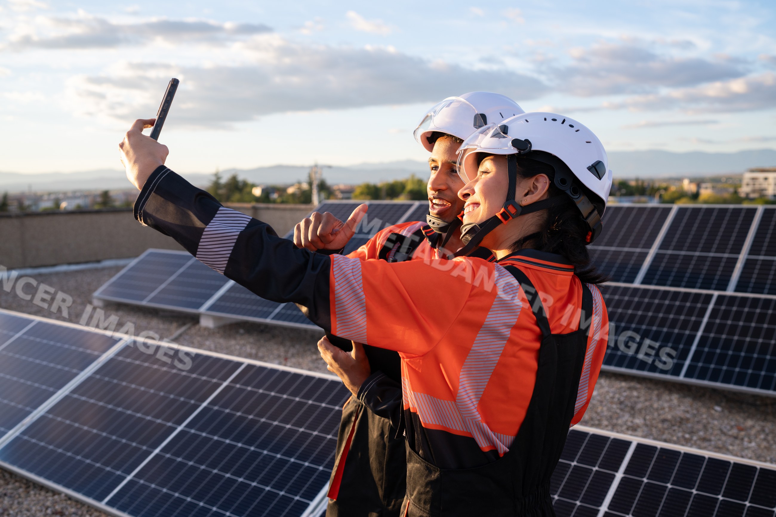Hispanic workers taking selfie on rooftop solar panel installation