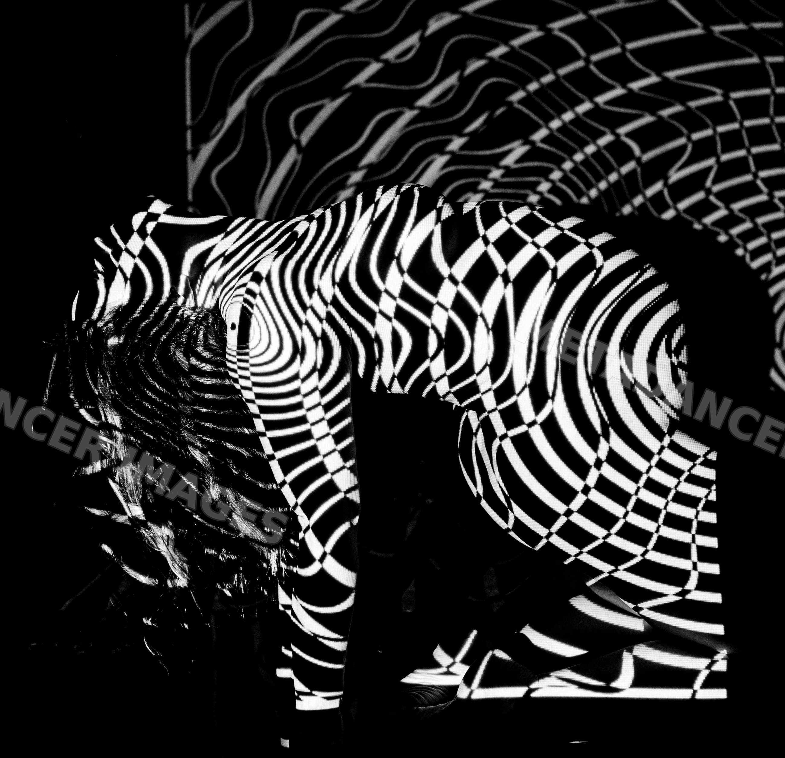 Woman kneeling with black and white striped optical illusion pattern