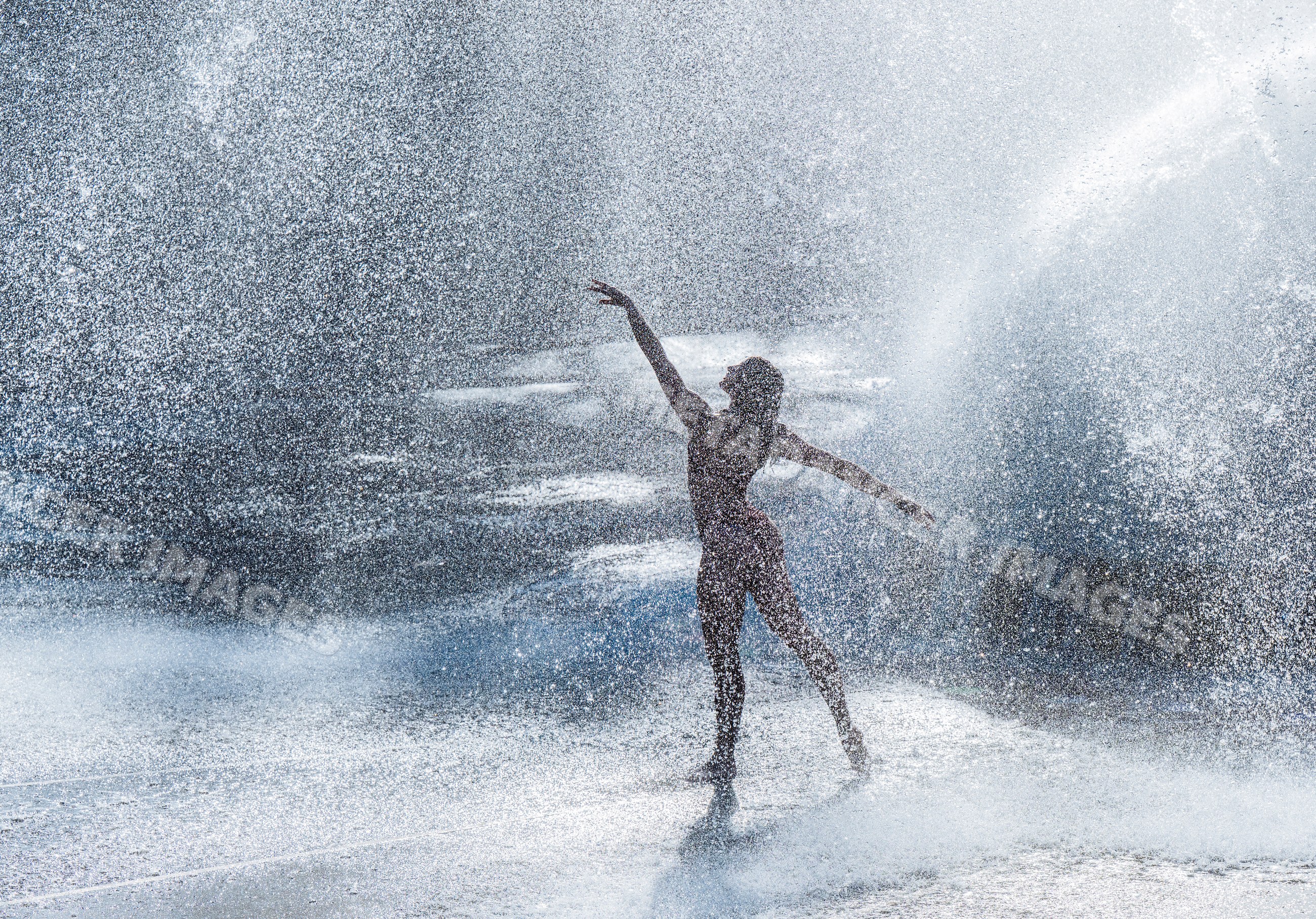 White woman dancing gracefully through splashing water outdoors