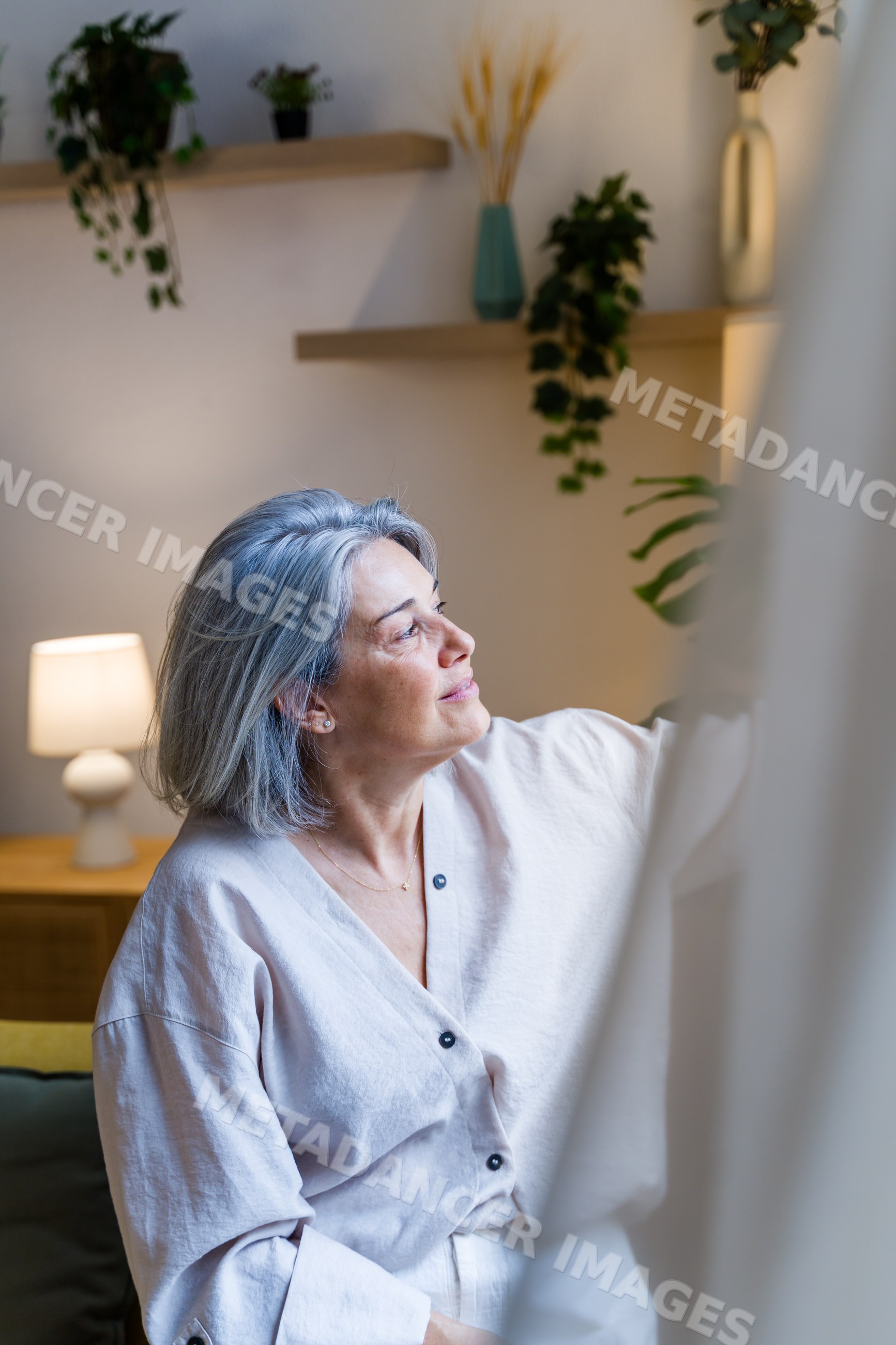 White woman with gray hair sitting contemplatively in living room