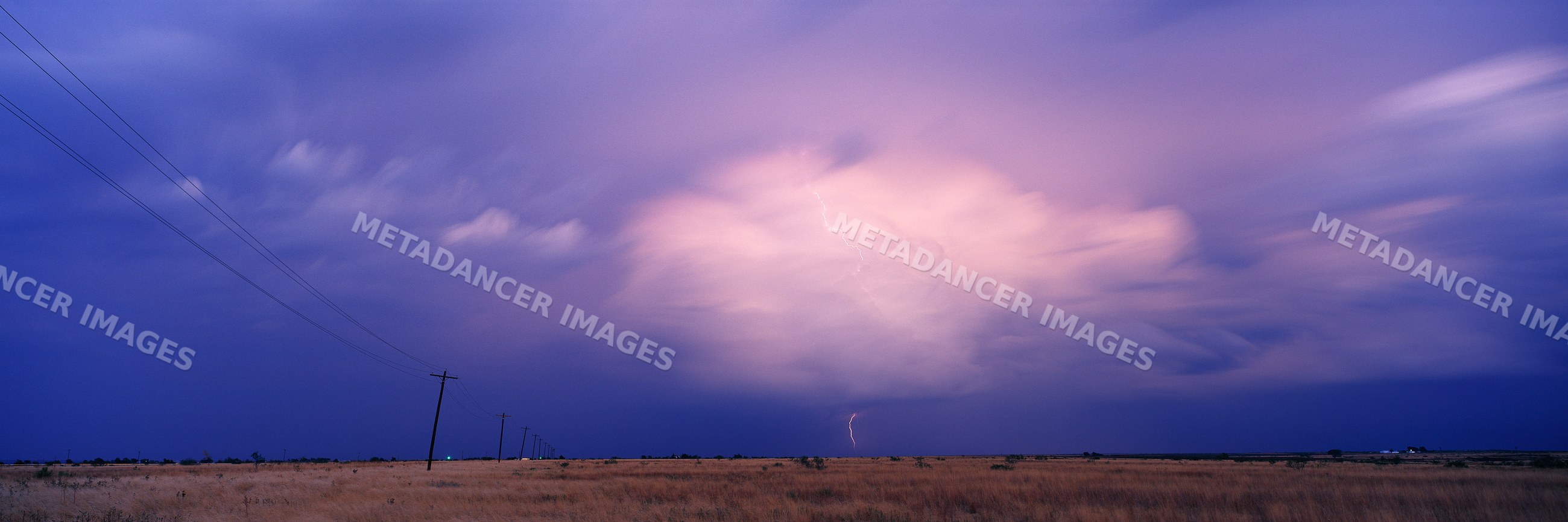 Thunderhead cloud with lightning over dry grass field