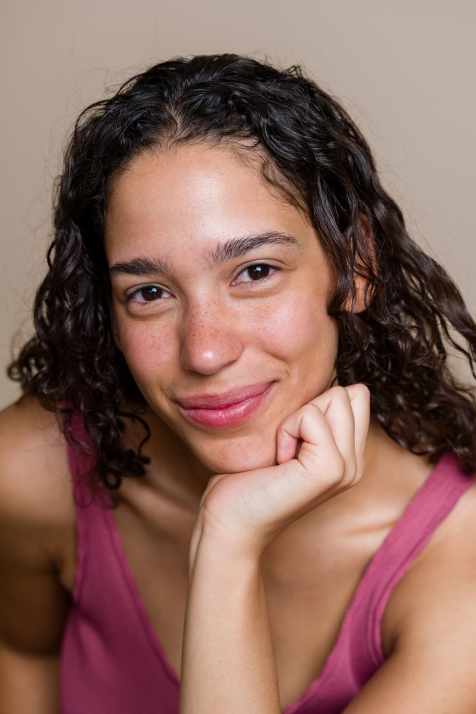 Hispanic woman with curly hair smiling in studio portrait