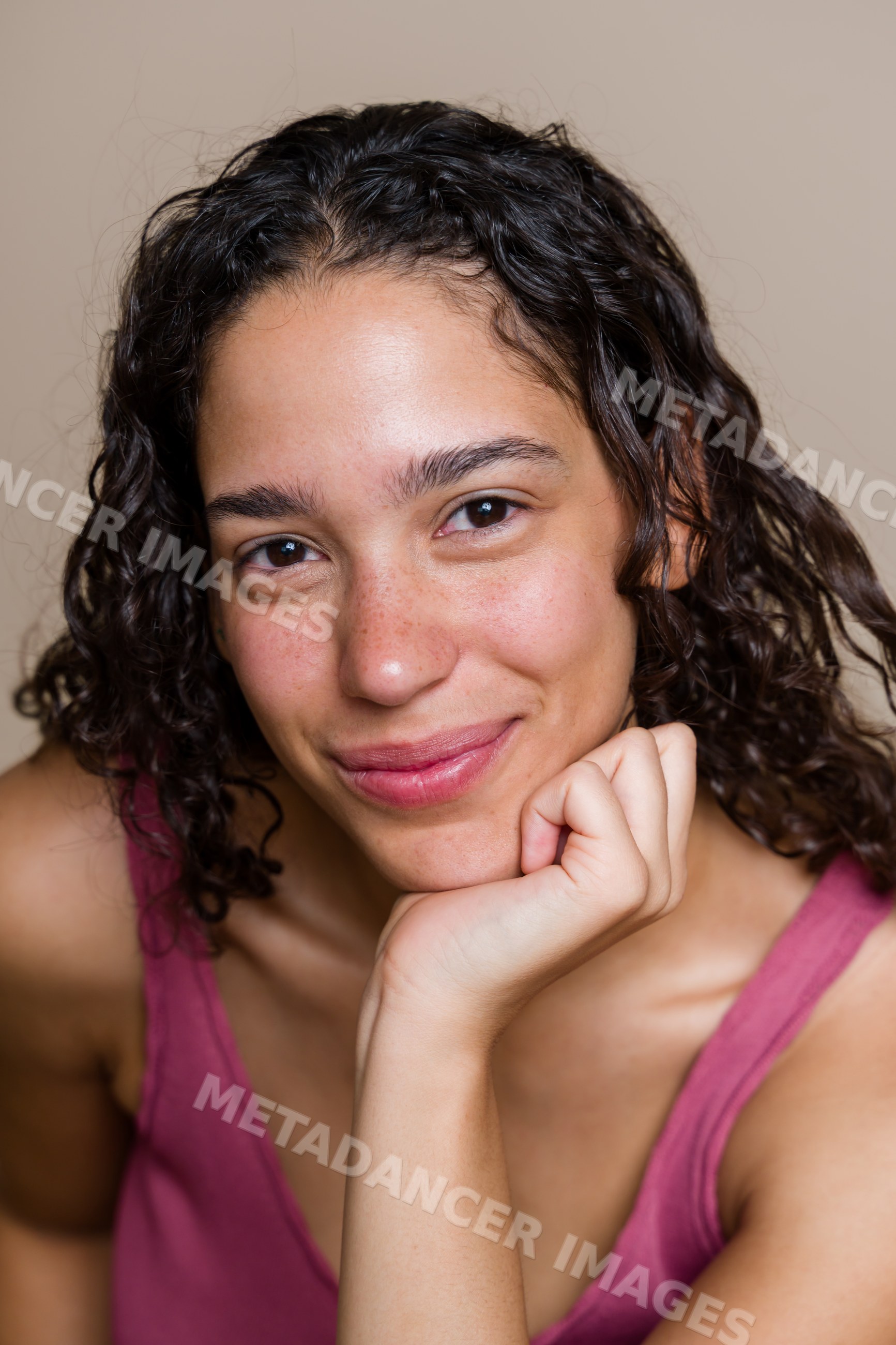 Hispanic woman with curly hair smiling in studio portrait