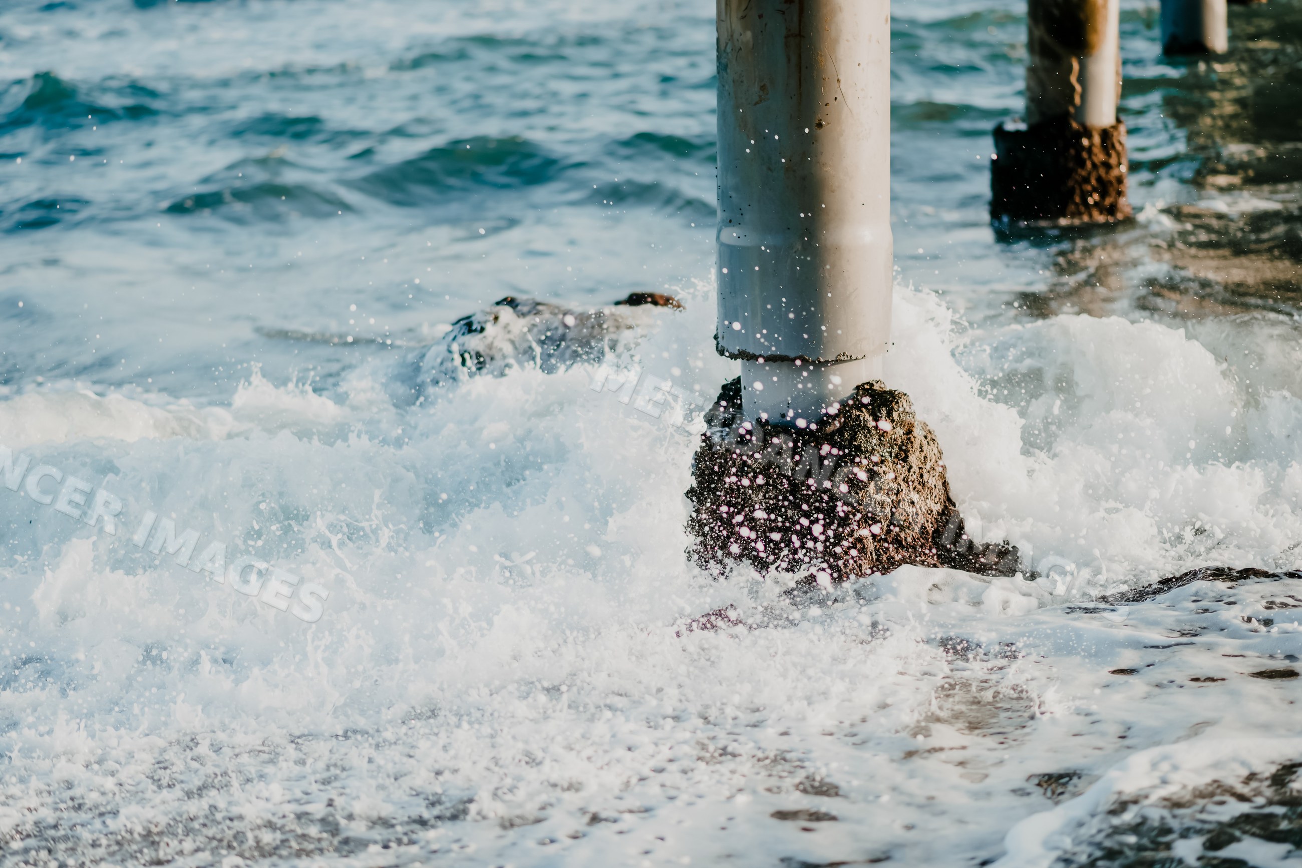 Waves crashing on pier pillars in ocean water at coastal Spain