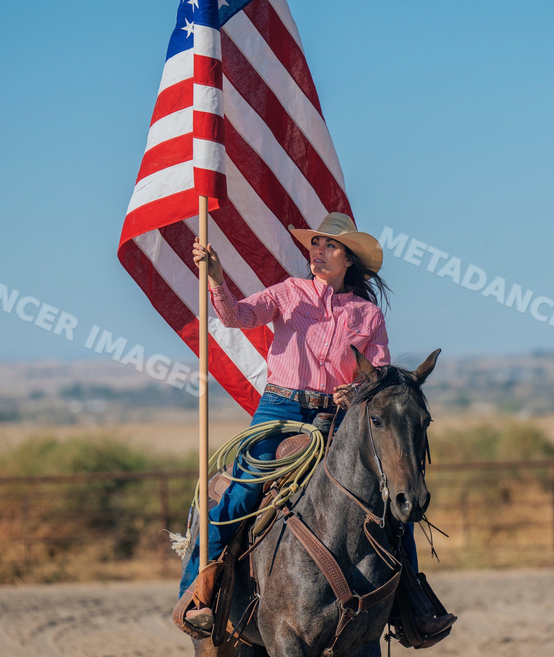 White woman on horse holding american flag in Southwest USA ranch