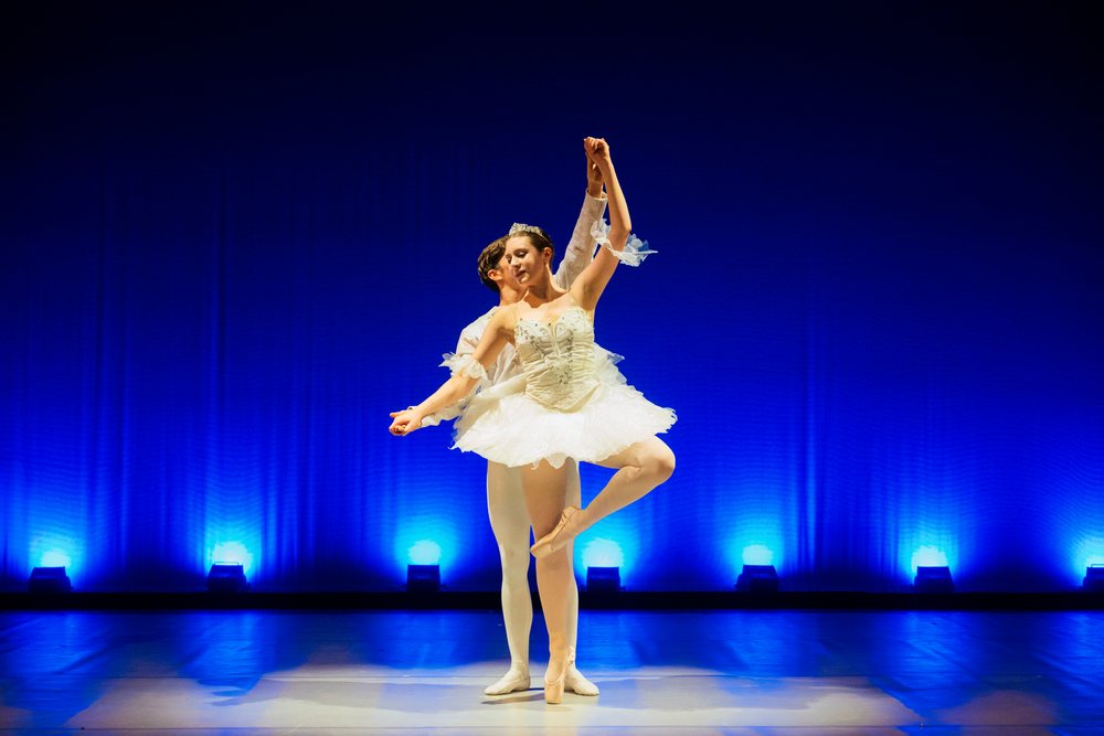 Male and female ballet dancers perform a graceful pose