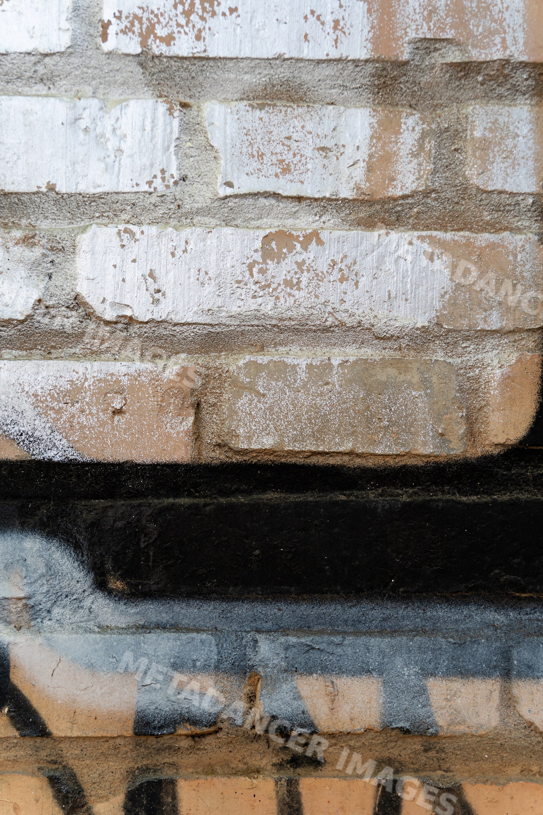 Rough brick wall with weathered white and black paint textures