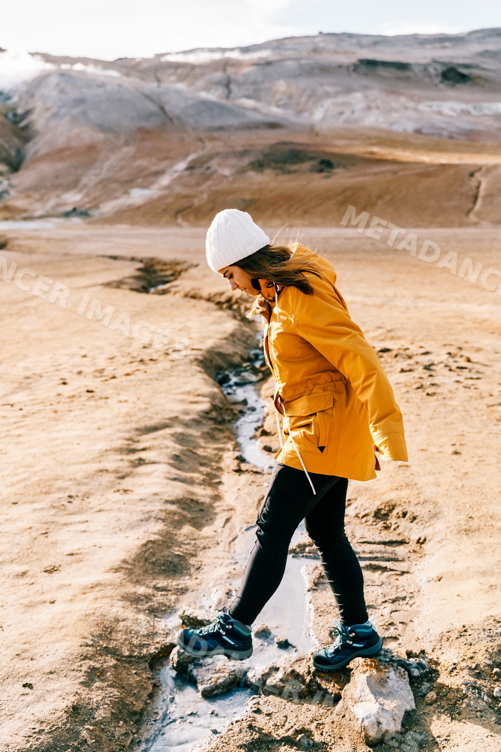 A white woman hiking over muddy terrain