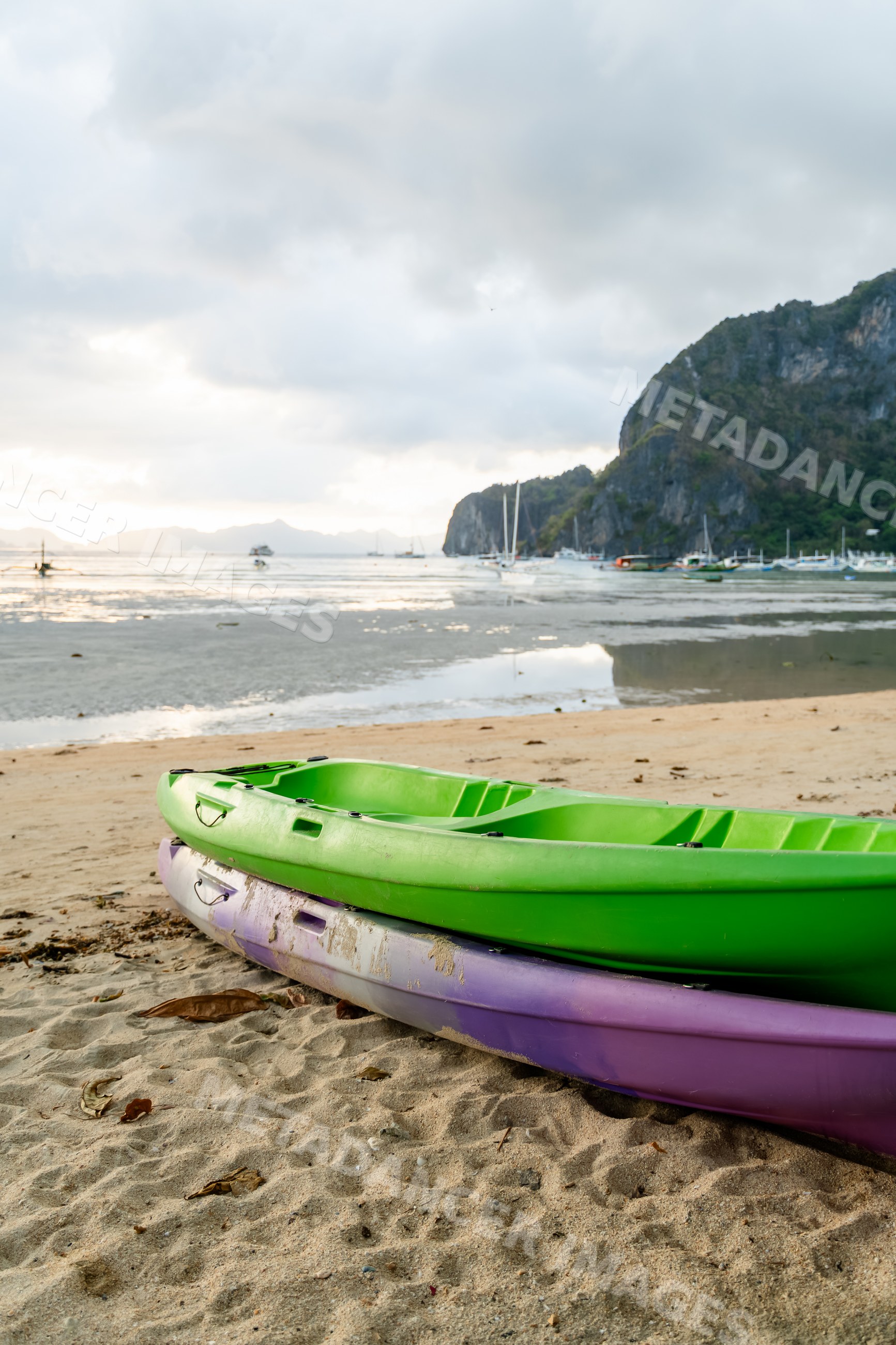 Kayaks stacked on beach at bay with mountain scenery in a beach