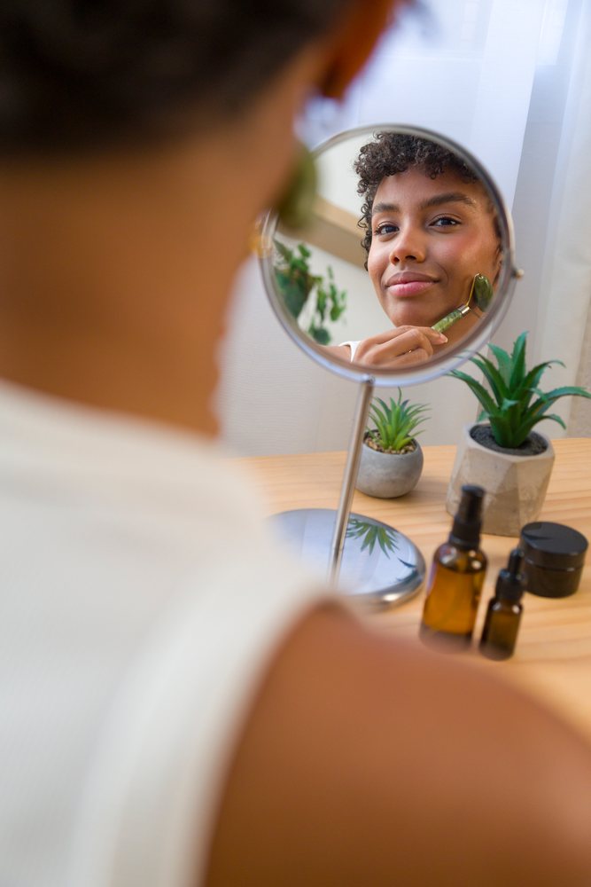 African American woman massaging face with jade roller