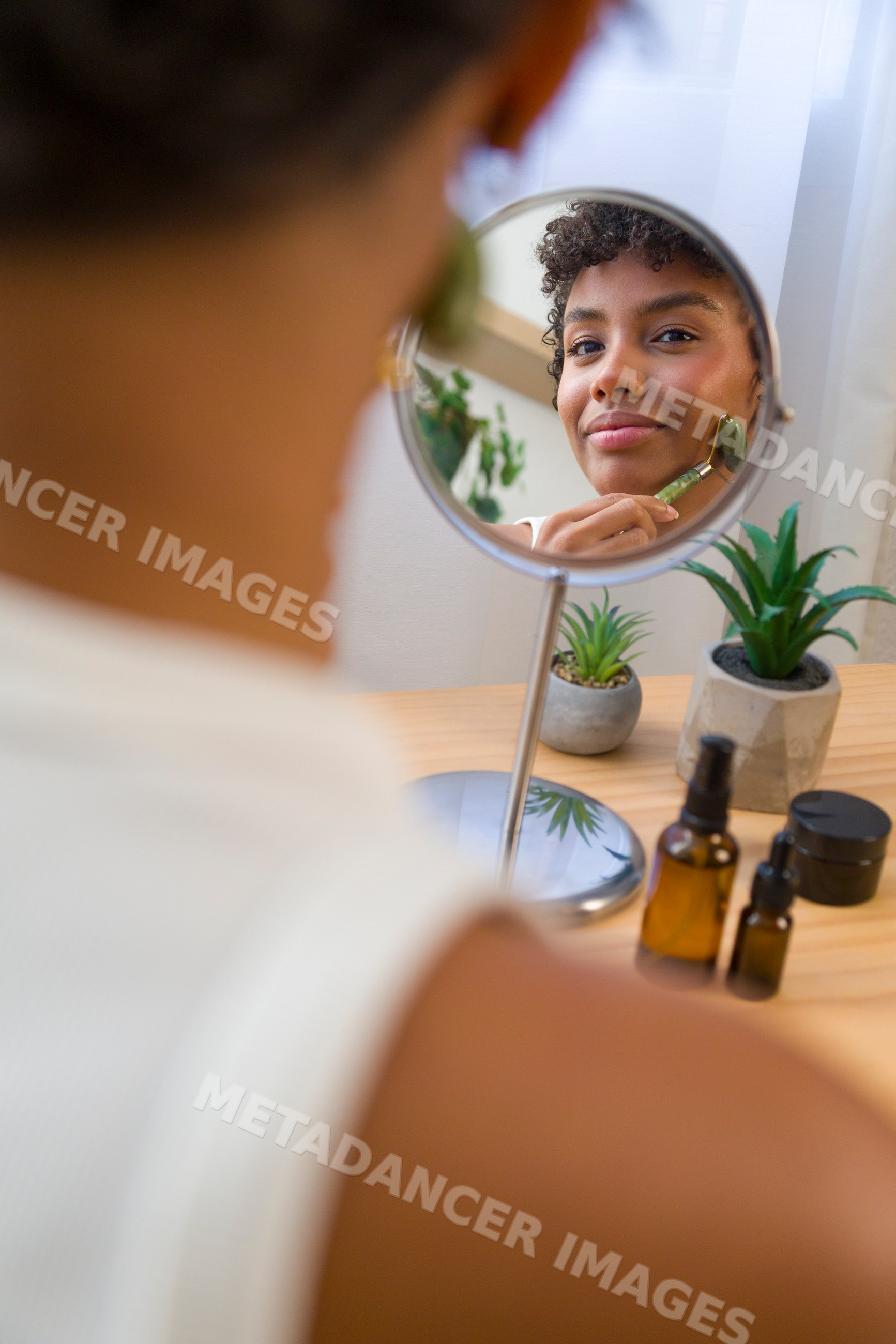 African American woman massaging face with jade roller