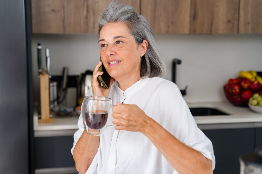 Mature white woman talking on phone with coffee