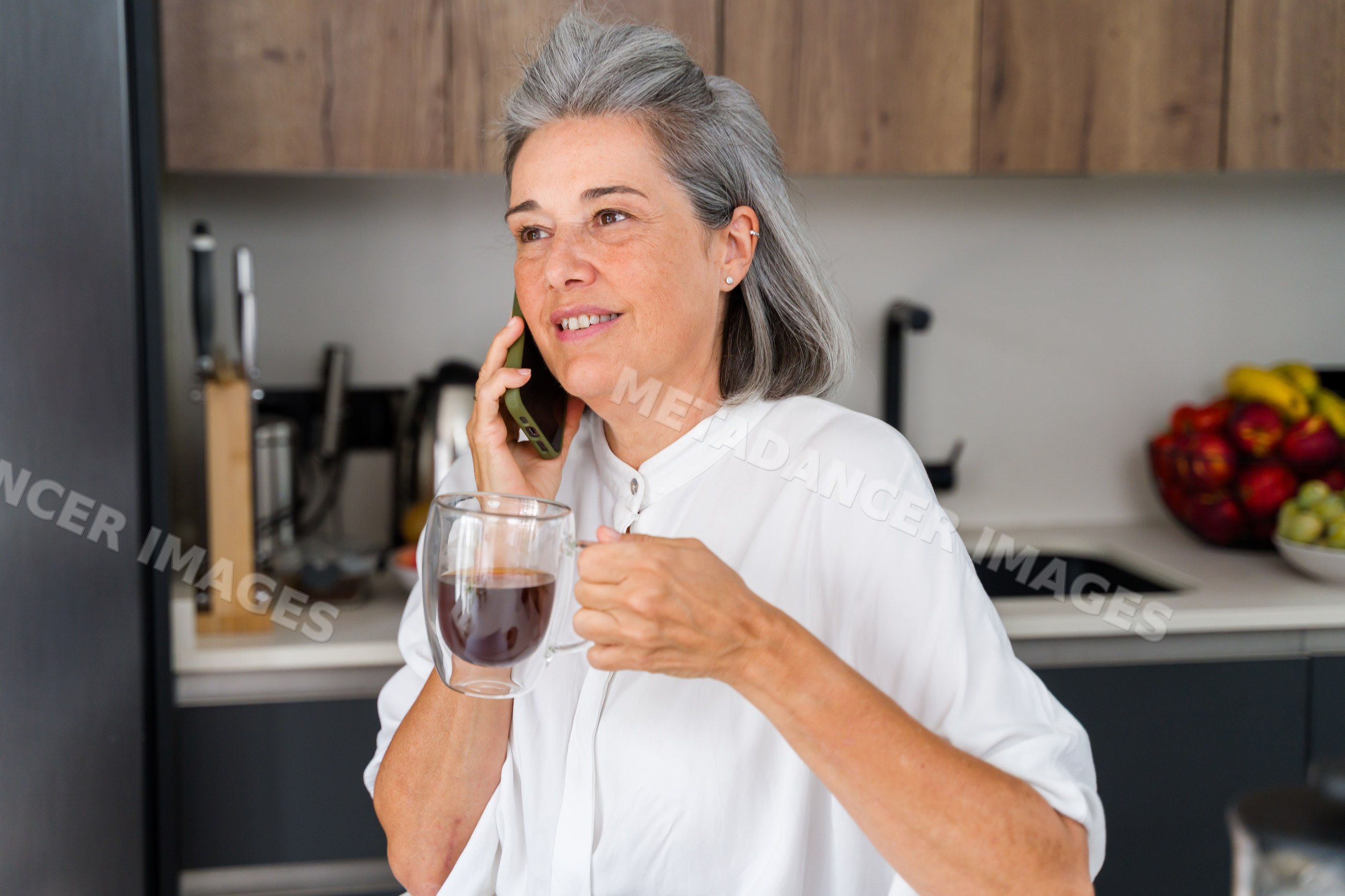 Mature white woman talking on phone with coffee
