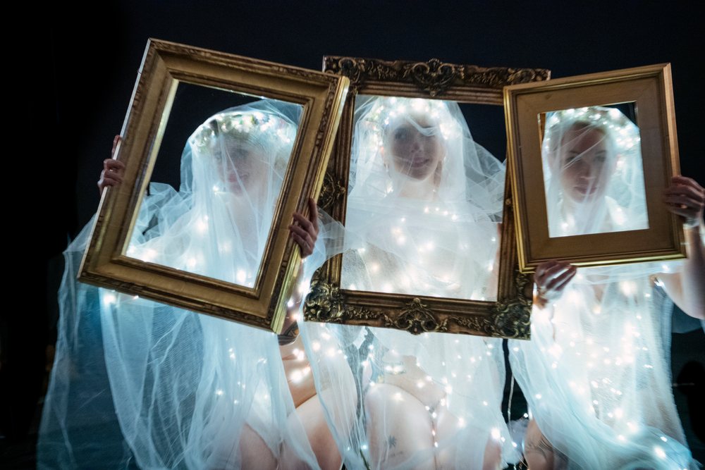 Muses holding illuminated picture frames in veils at night