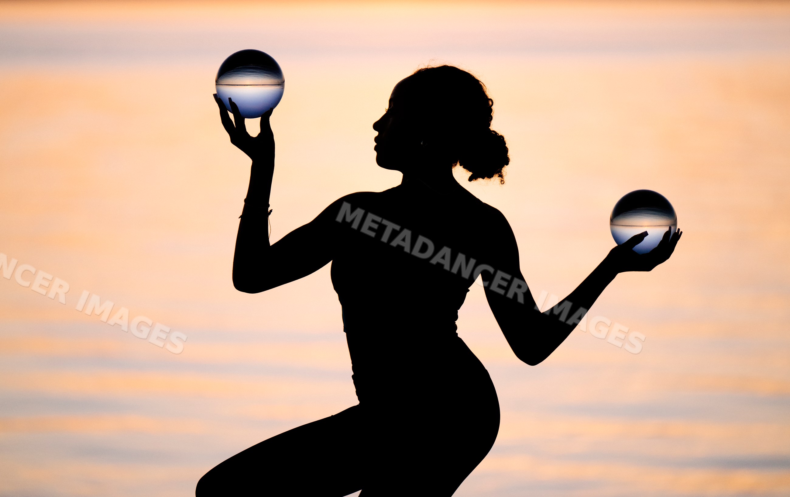 Silhouette of Hispanic woman performing yoga with glass balls