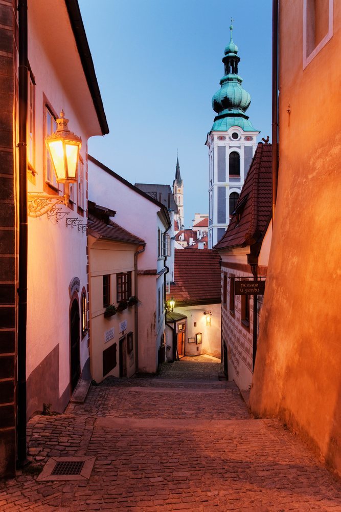 Narrow cobblestone street and church tower, bohemia