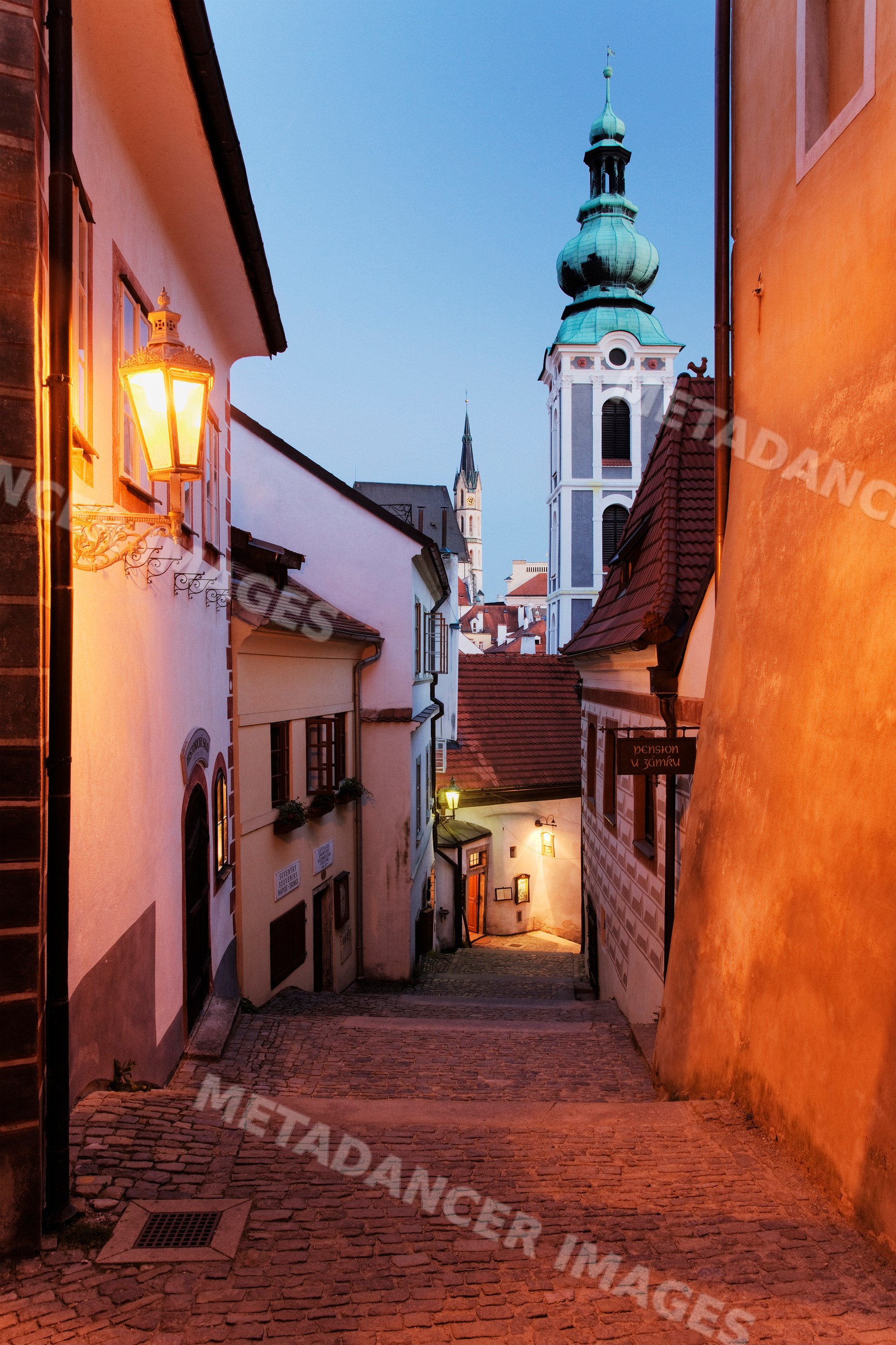Narrow cobblestone street and church tower, bohemia