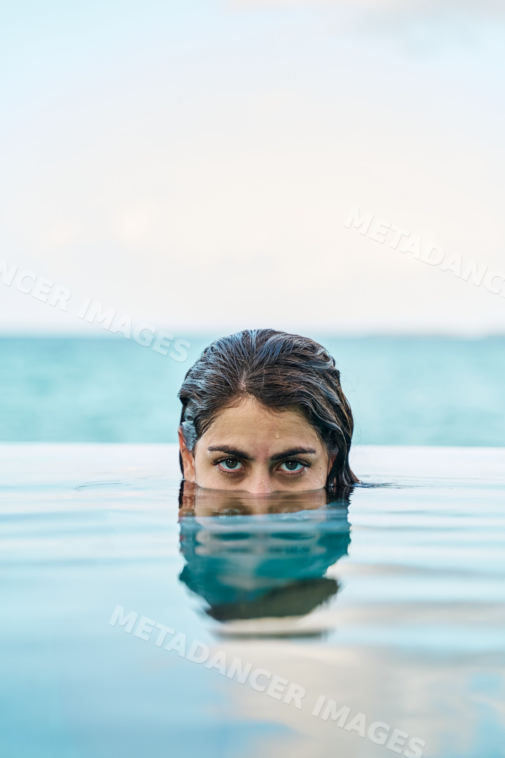 A white woman swims in an outdoor pool with calm water