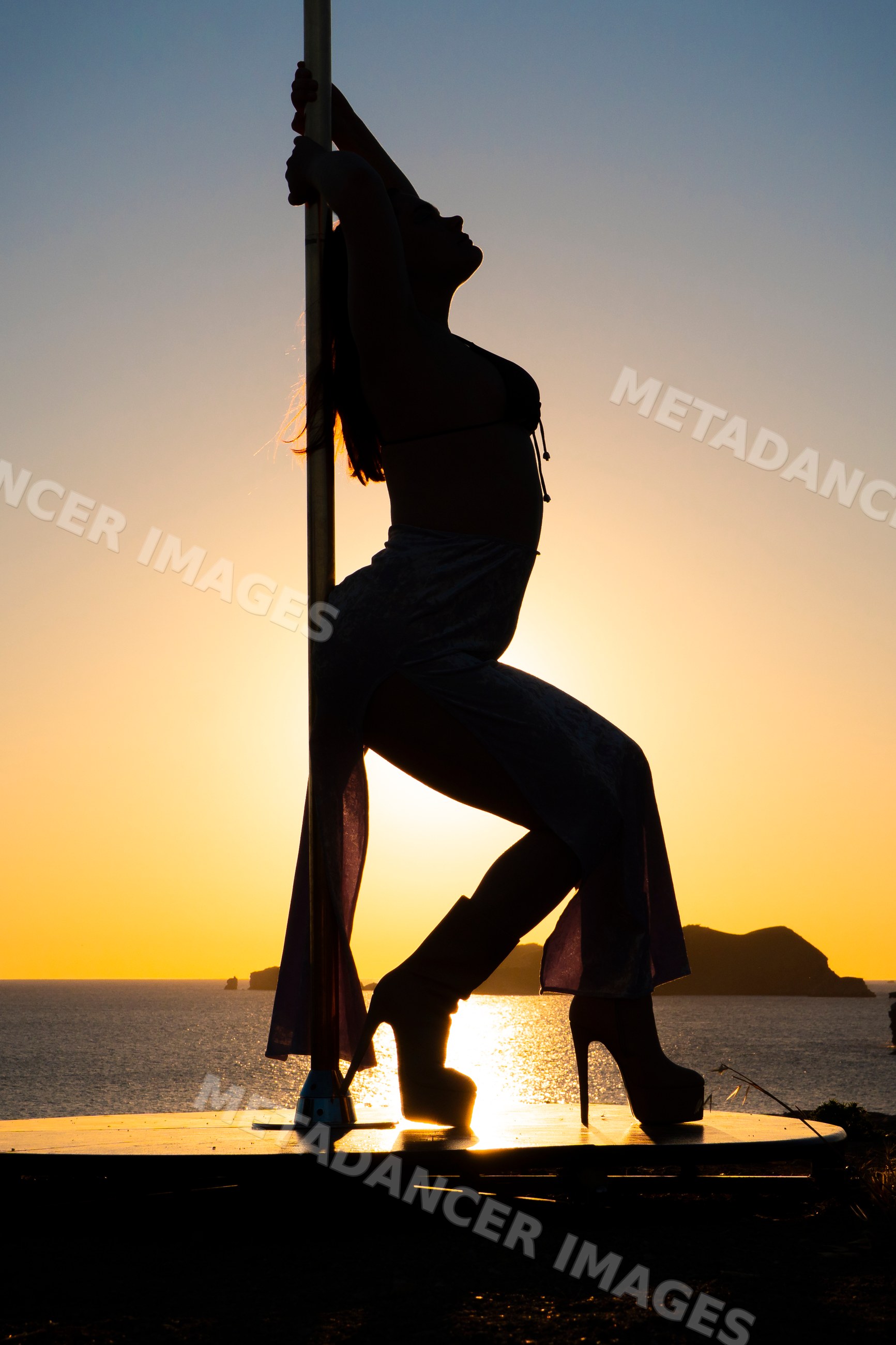 Female Pole Dancer silhouette performing at sunset on Ibiza coast