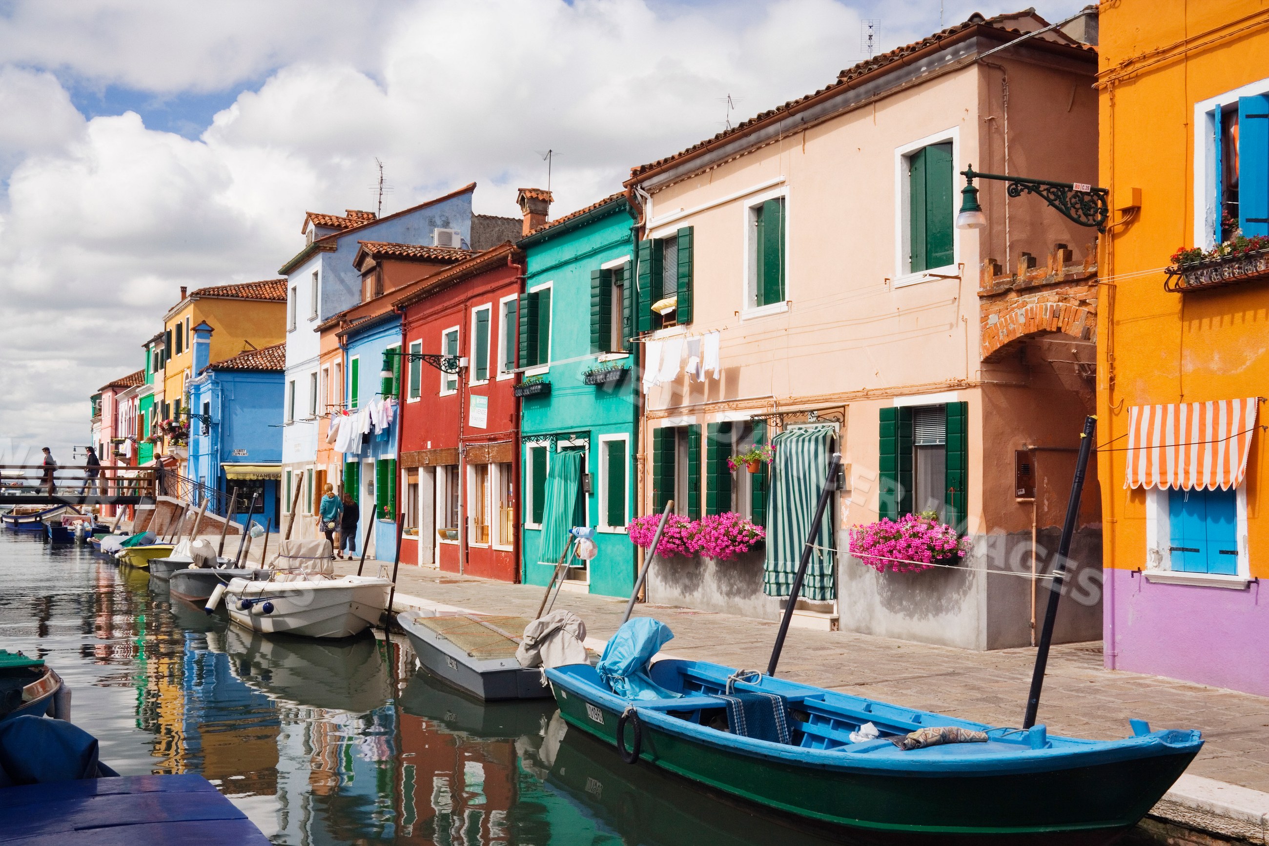 Boats anchored on canal with colorful houses, italy