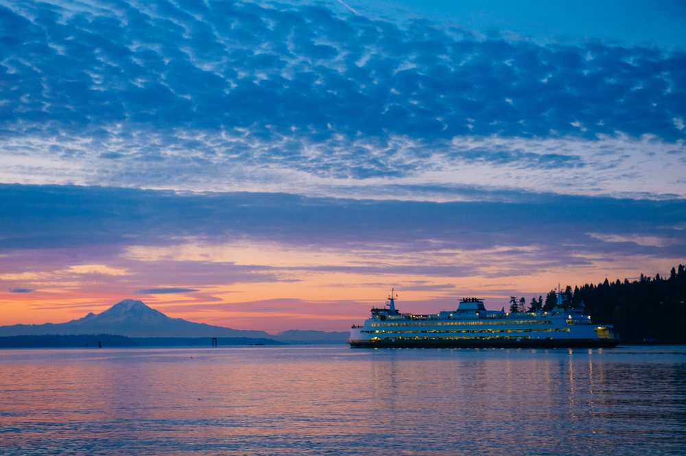Ferry crossing water at sunset with mount rainier in background