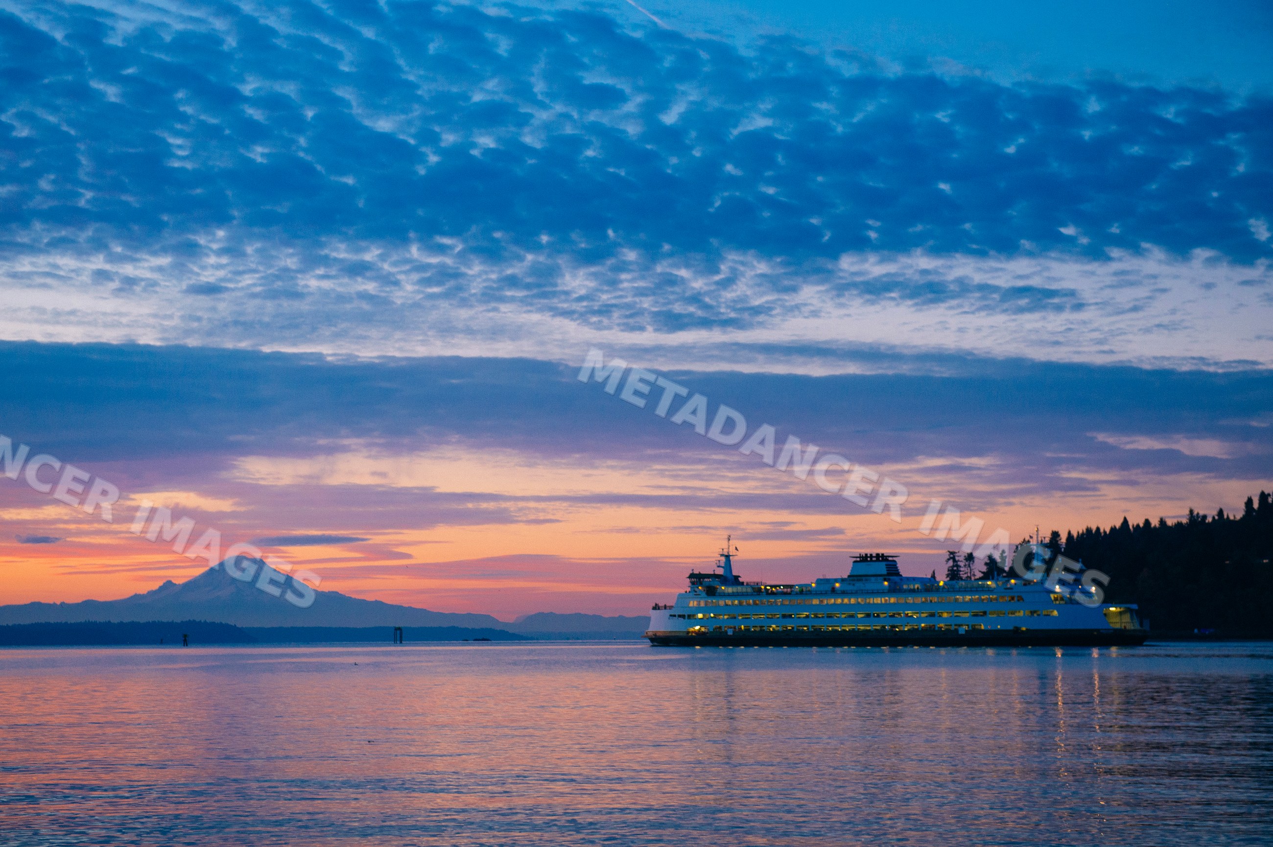 Ferry crossing water at sunset with mount rainier in background