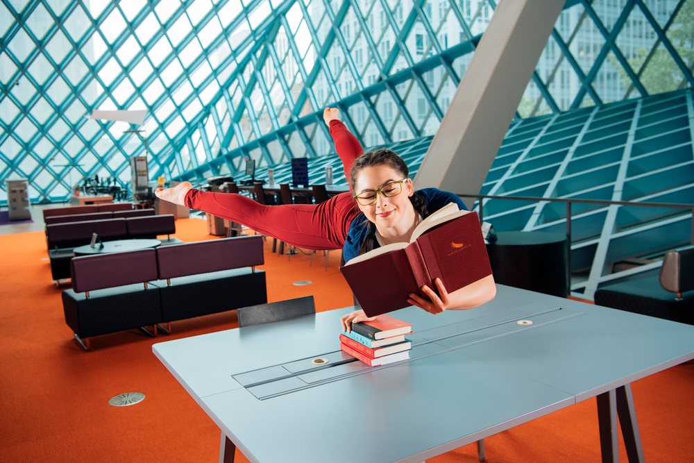 A woman reading a book while balancing on a table