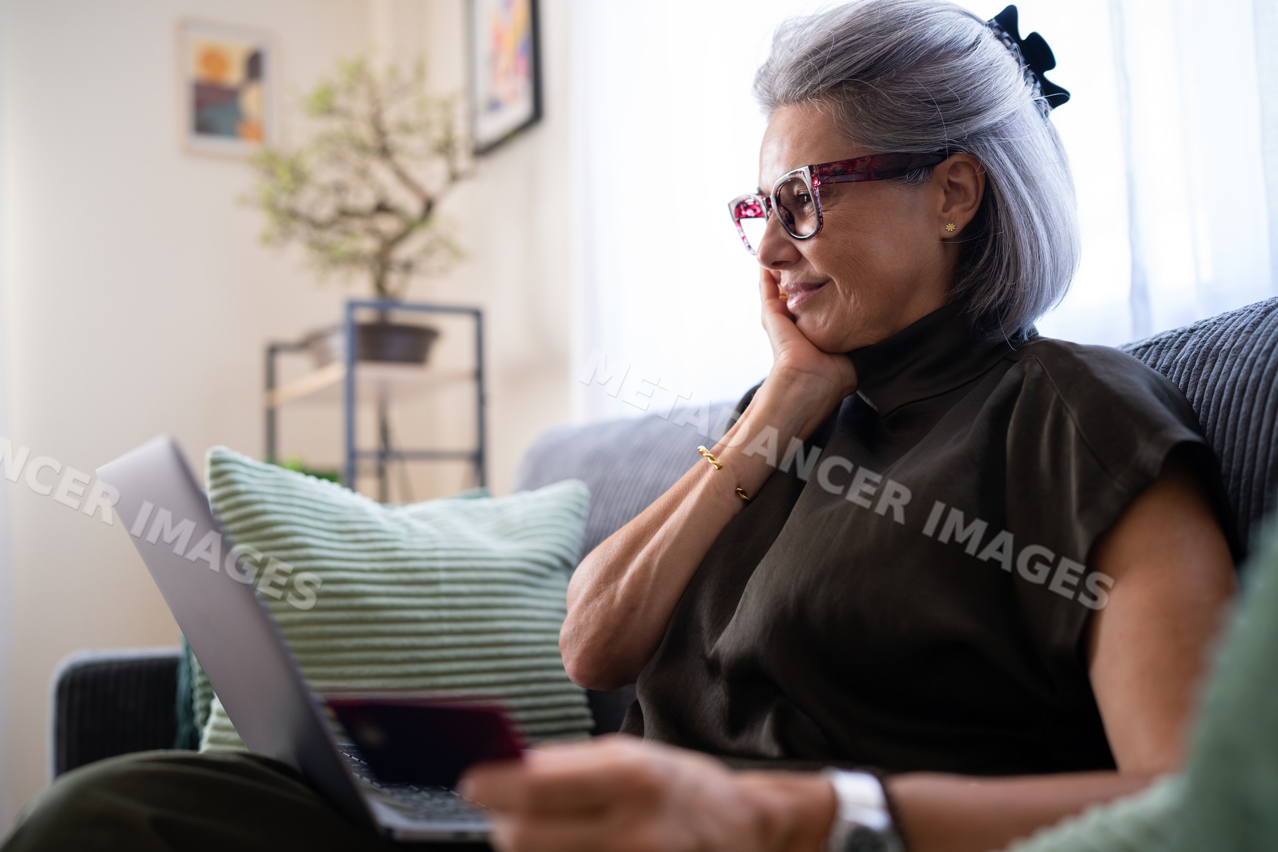 Mature white woman using laptop and credit card at home