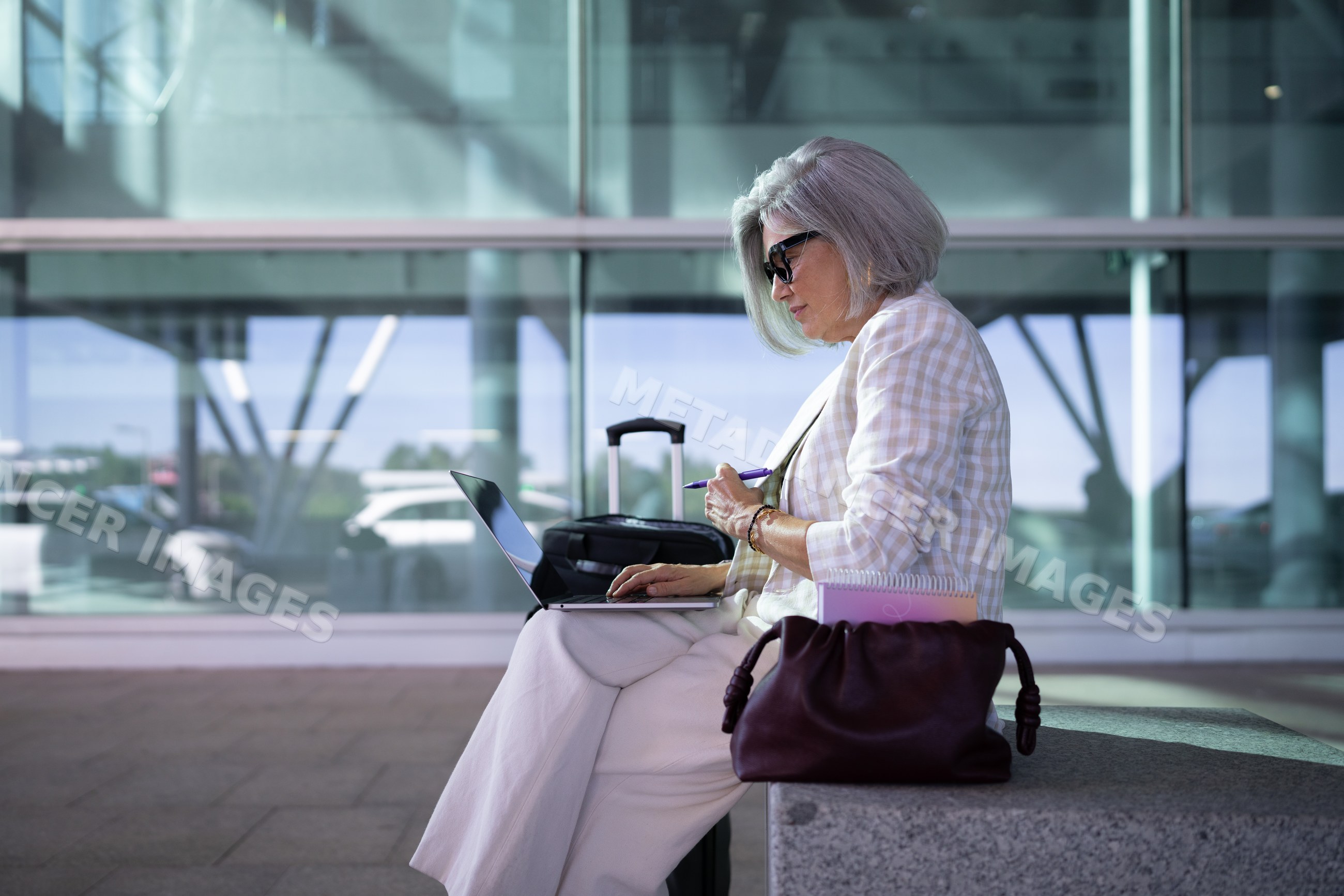 Businesswoman working on laptop in airport seating area