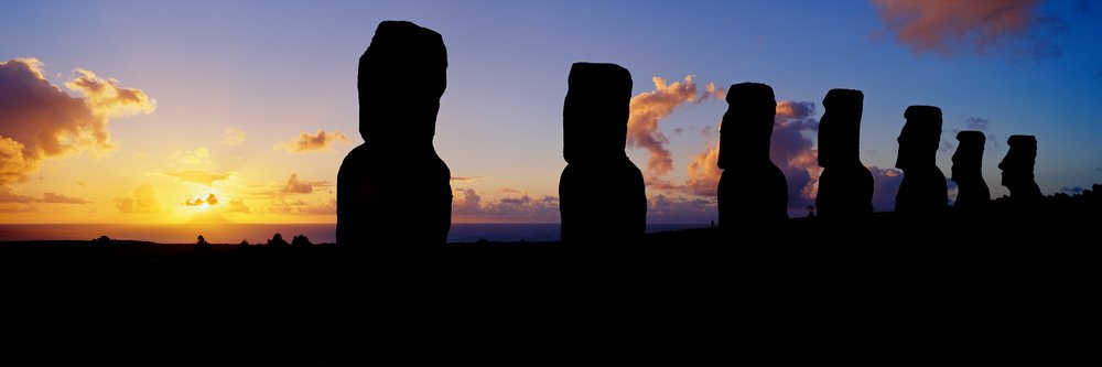 Silhouetted moai statues on easter island at sunset