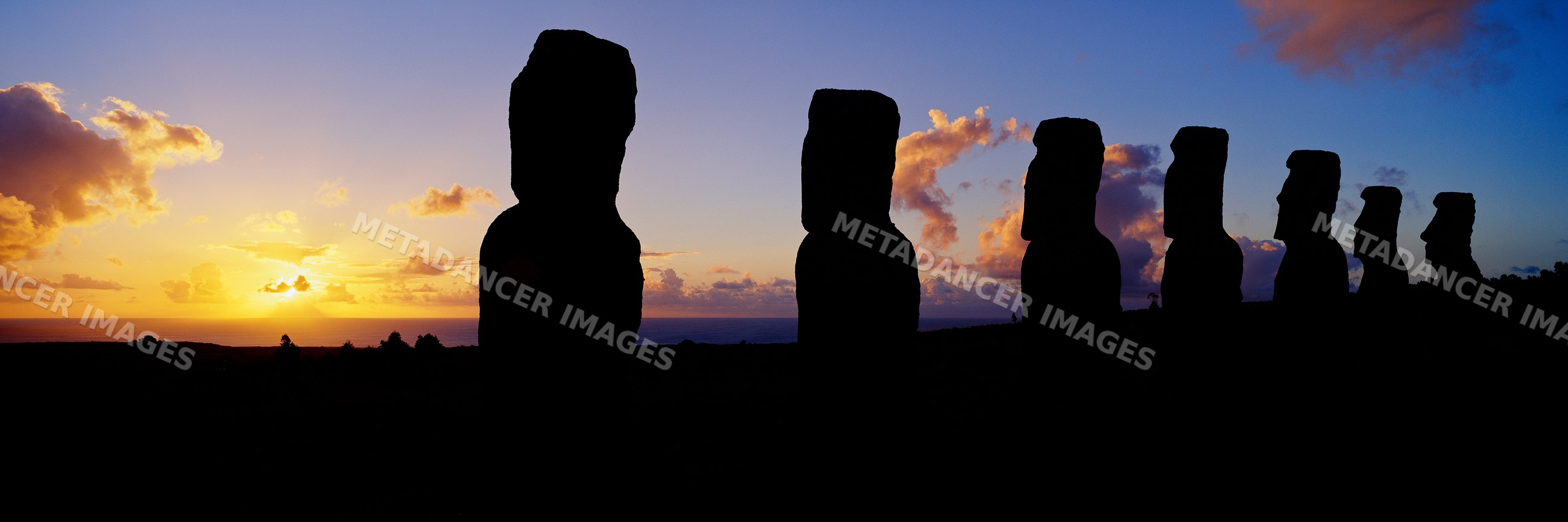 Silhouetted moai statues on easter island at sunset
