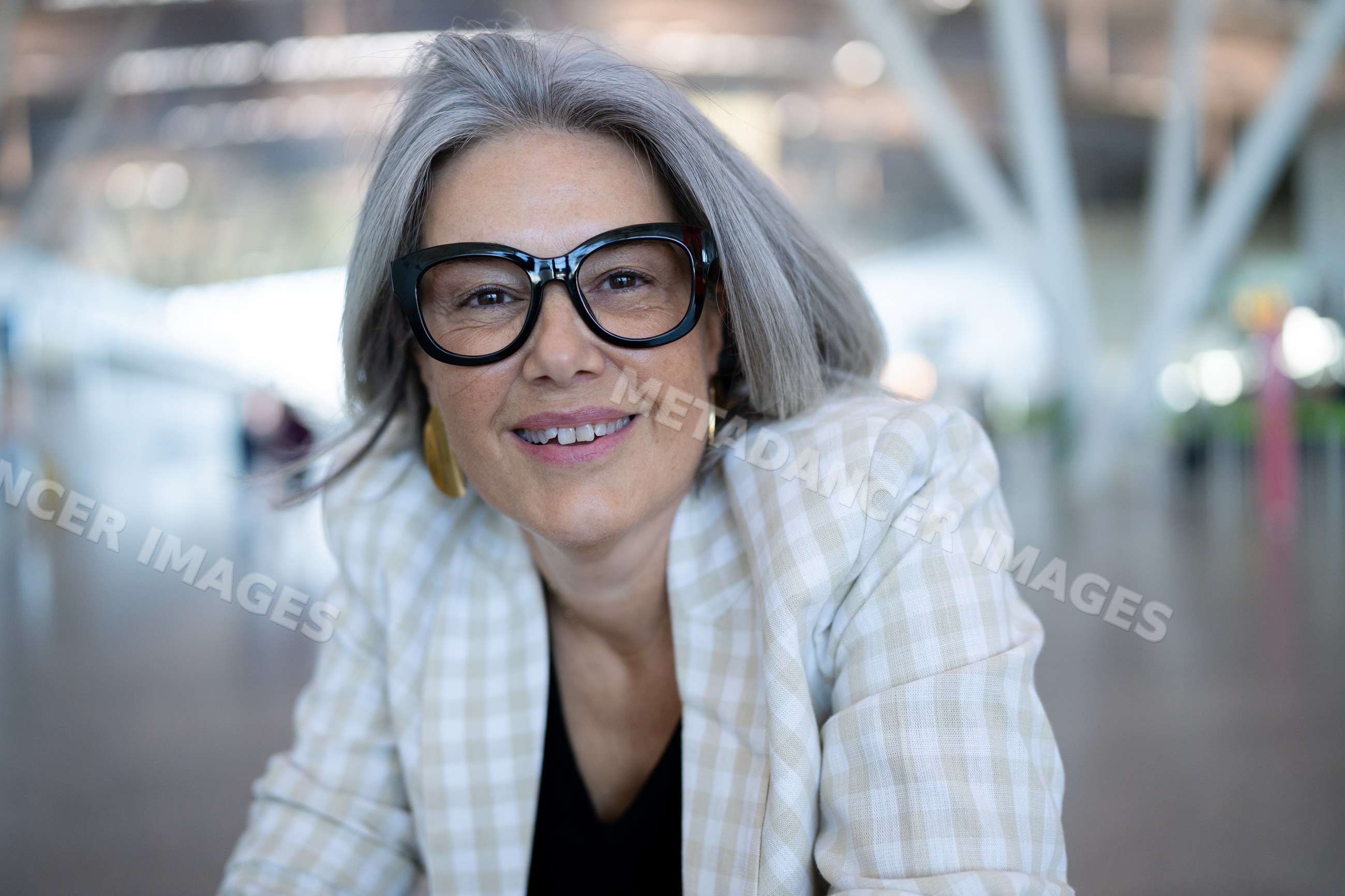 Middle-aged white woman with gray hair and glasses smiling indoors