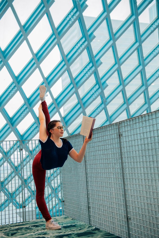 A woman stretches her leg while reading a book