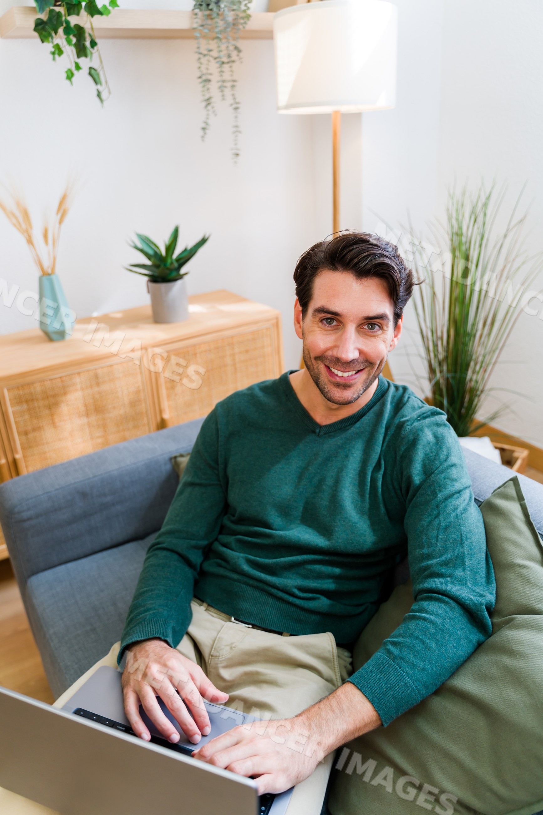 White man sitting on sofa using laptop in modern living room