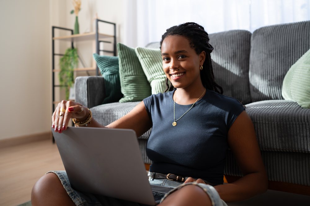 African American woman uses a laptop while sitting on the floor