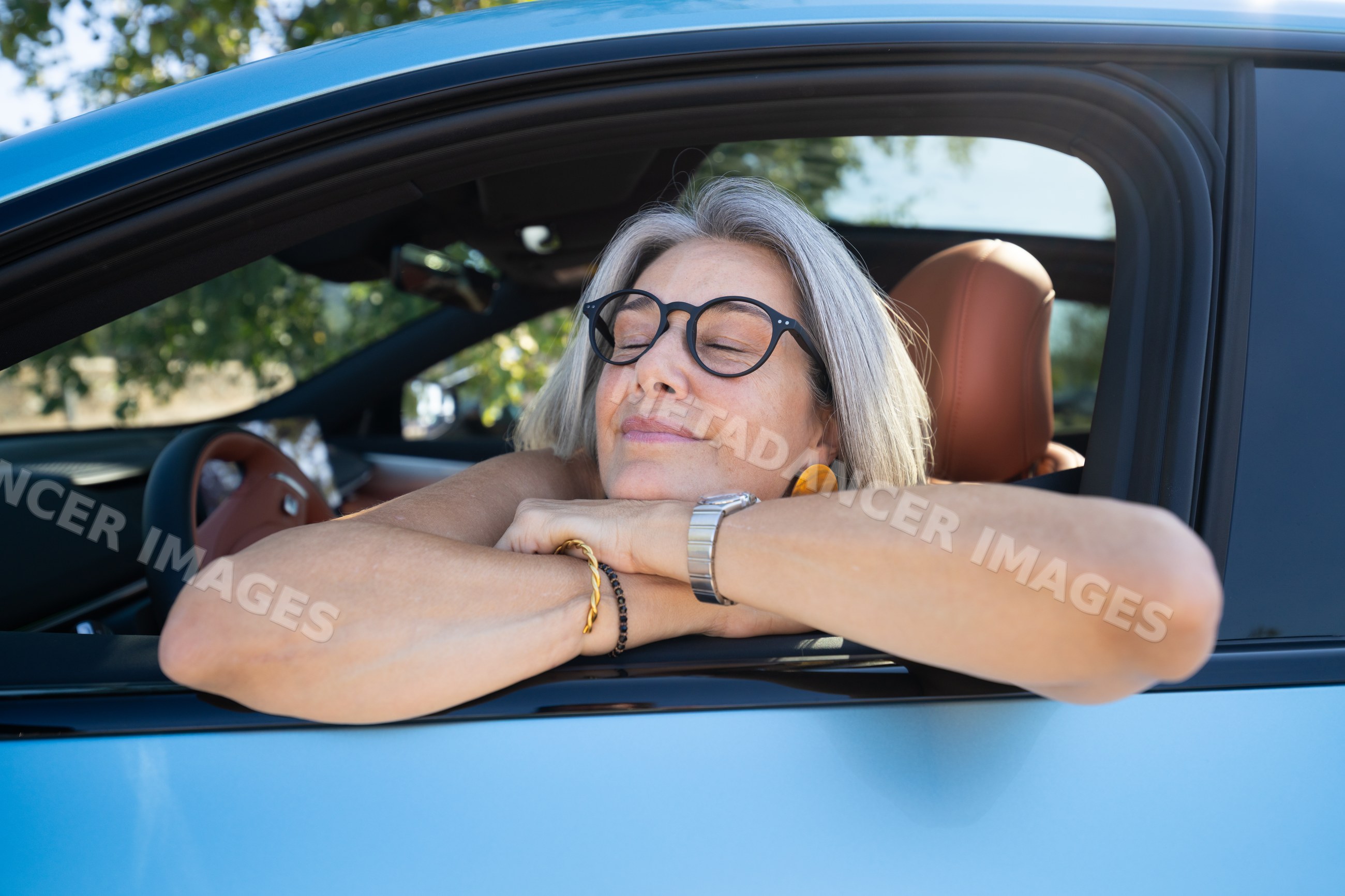 Mature white woman relaxing in blue car with eyes closed