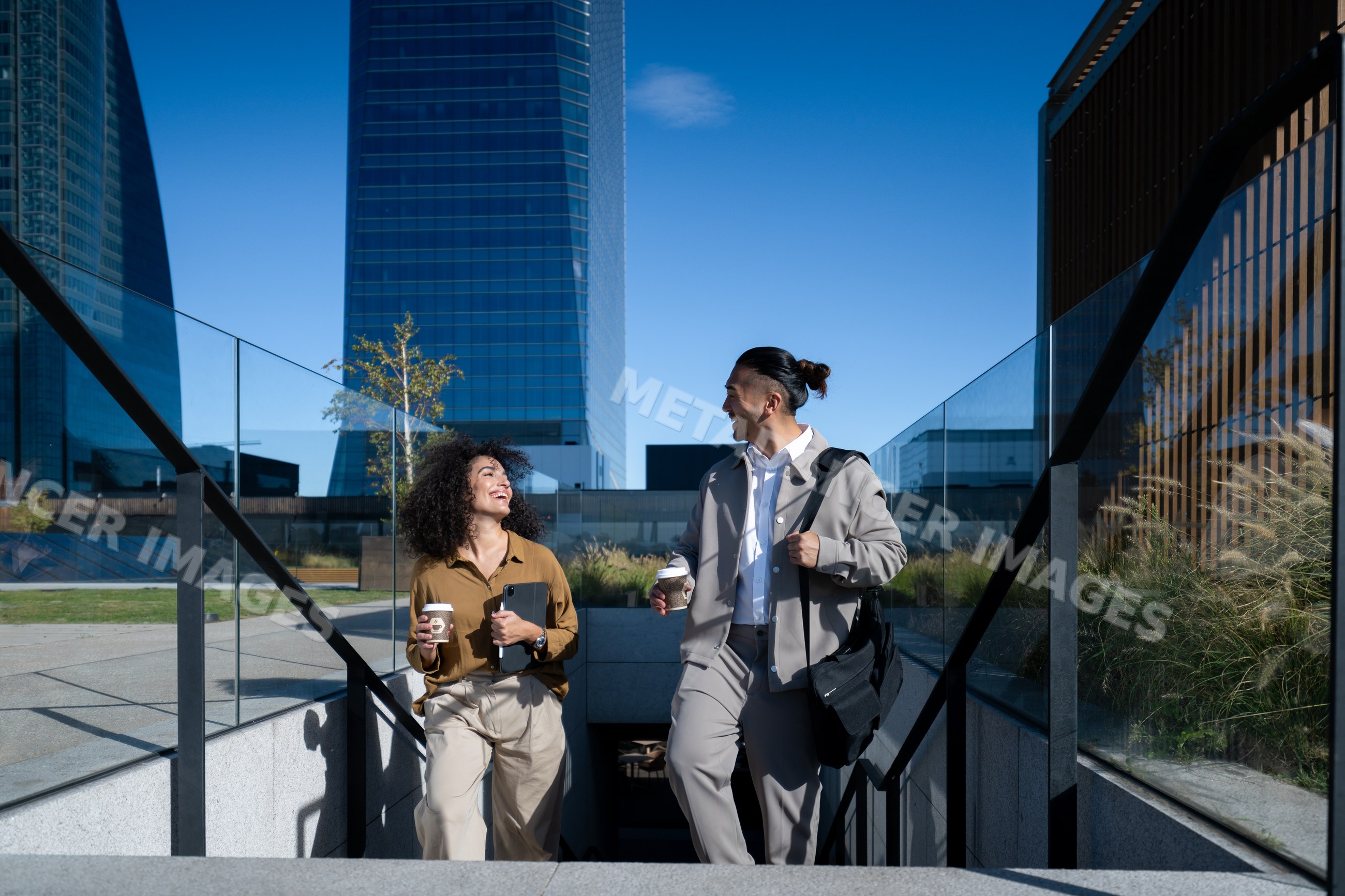 Two people walking up outdoor stairs with coffee in urban area