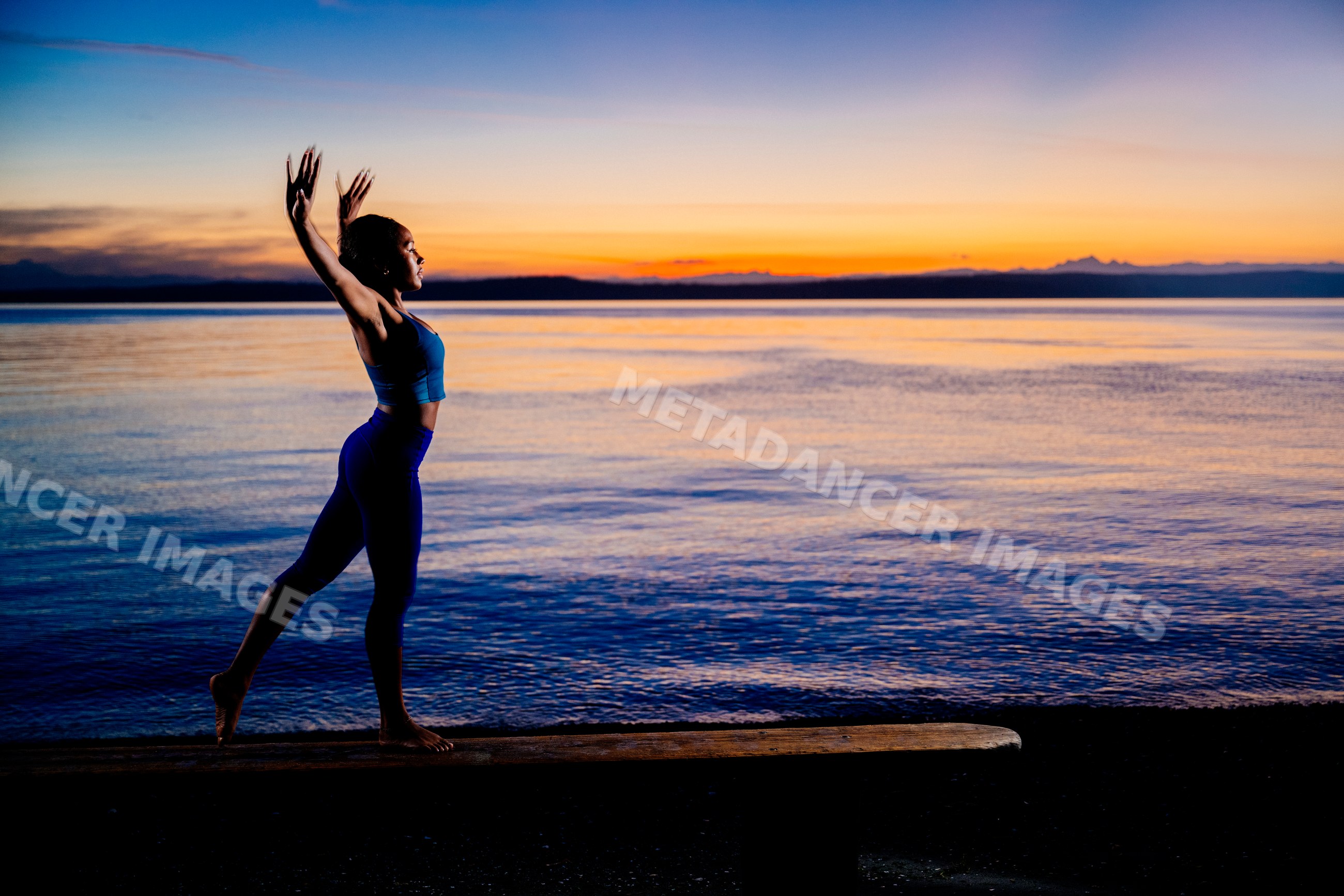 Hispanic woman practicing yoga balance pose at sunset near lake in USA