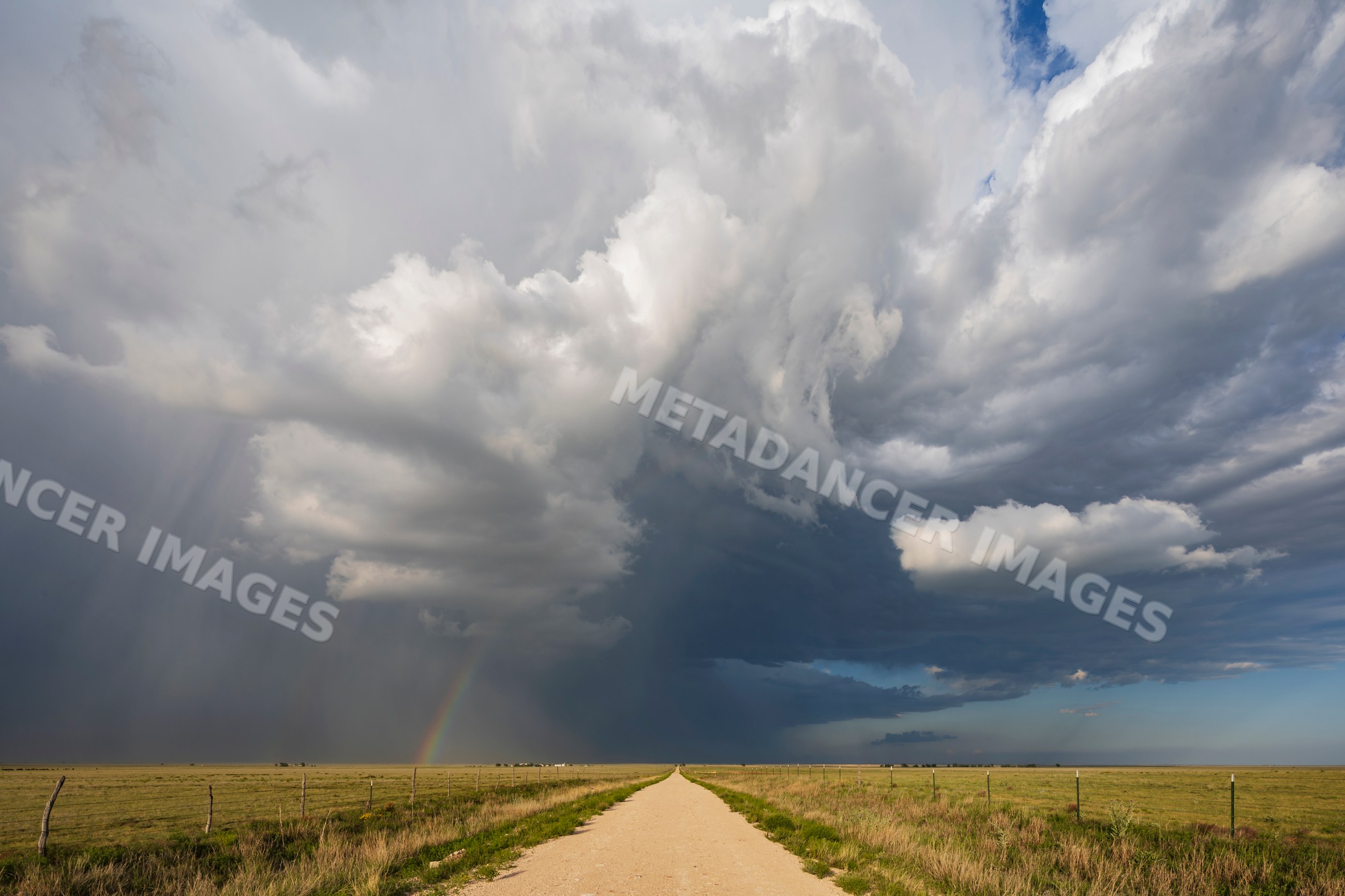 Supercell storm with Rainbow over grassland dirt road