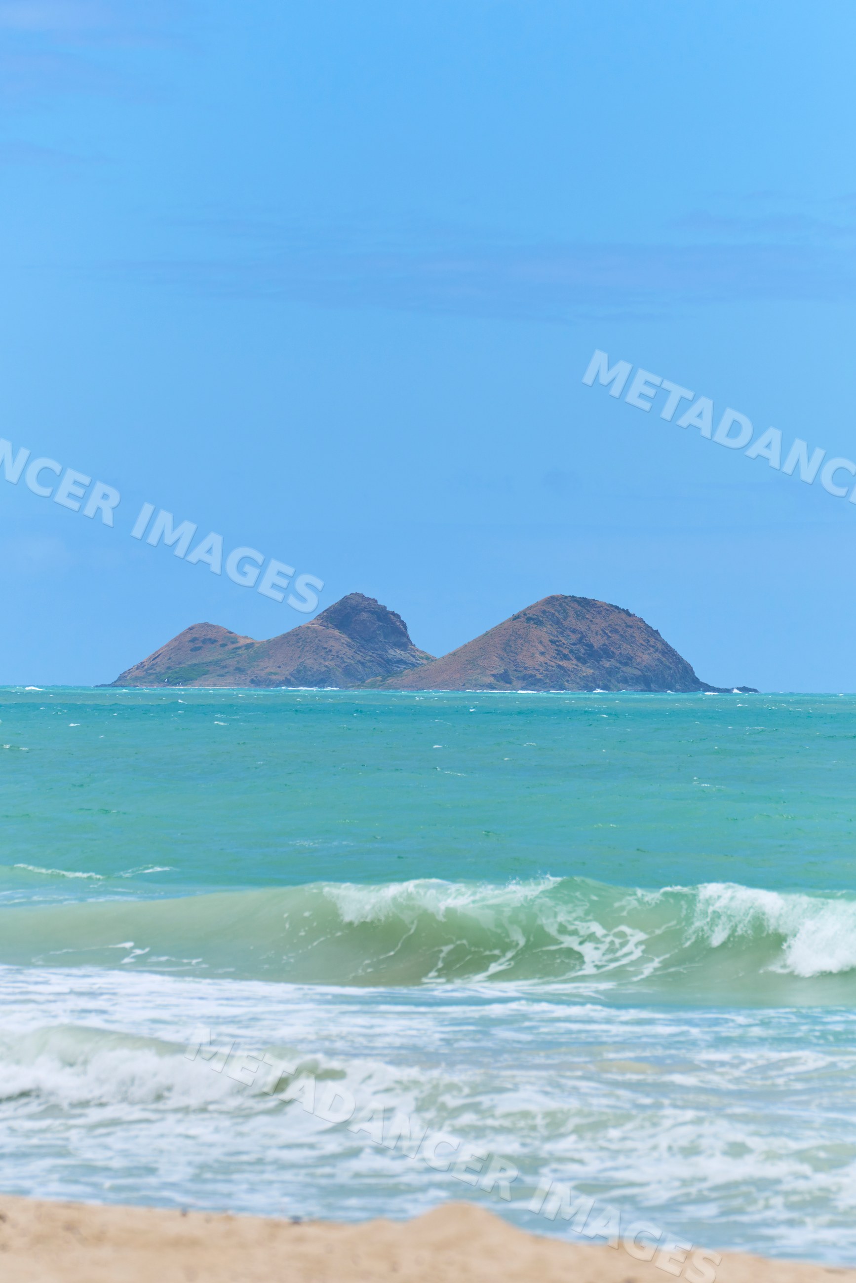 Ocean waves and islands viewed from sandy beach in a beach