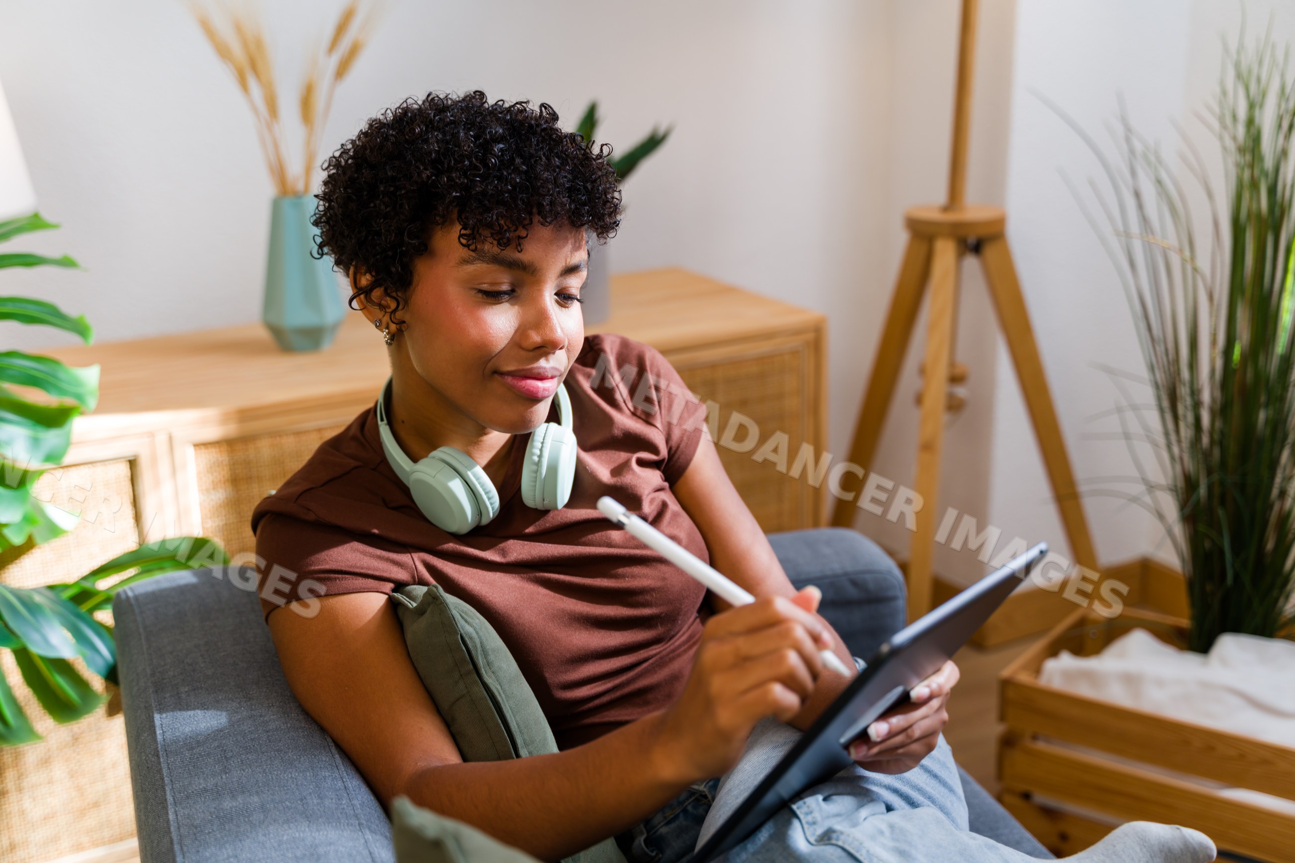 African American woman using tablet with stylus pen on couch