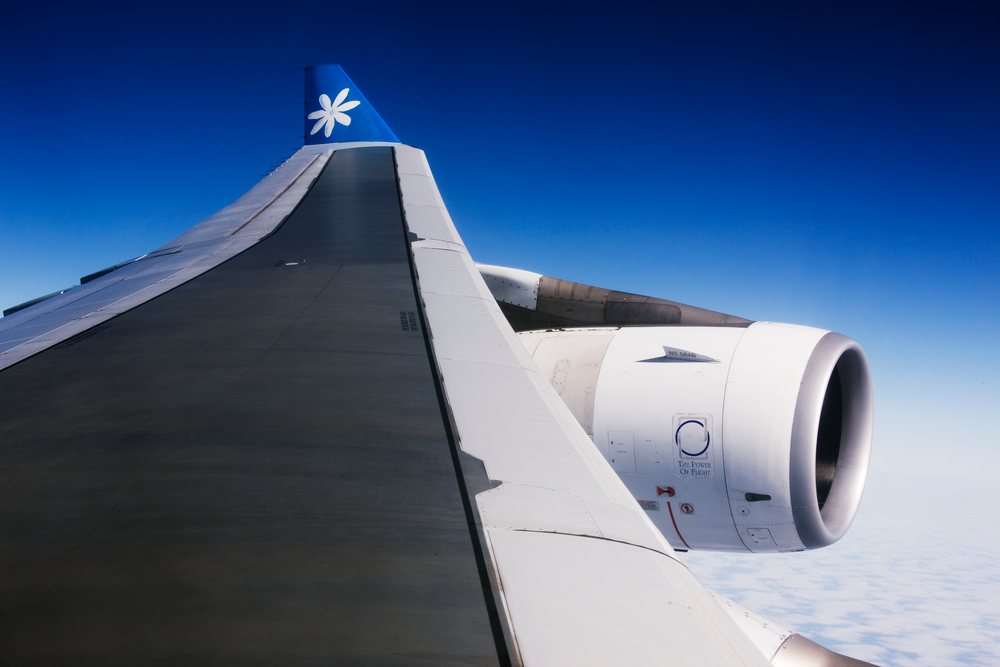 Airplane wing and jet engine flying over clouds