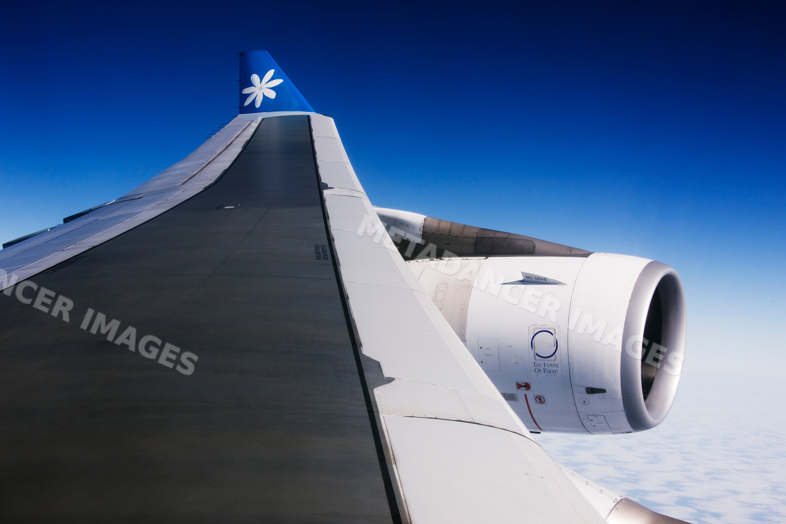 Airplane wing and jet engine flying over clouds