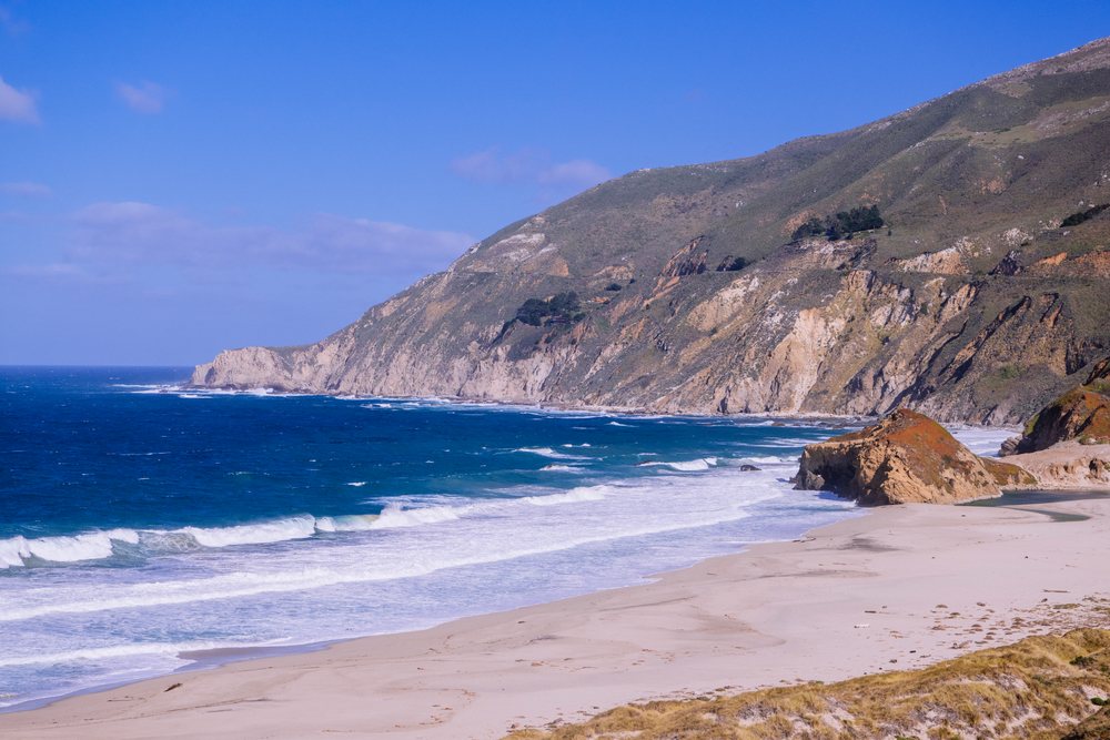 California coast rocky cliffs and sandy beach with ocean waves