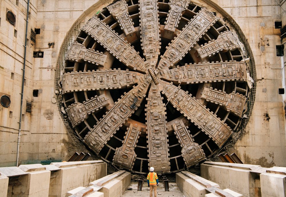 White Workers stand near a large tunnel boring machine