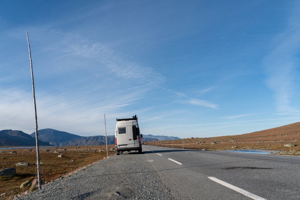 Van parked on road in mountainous landscape in Norway