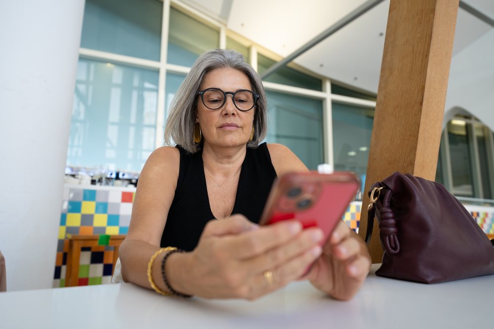 White woman with glasses using smartphone at indoor modern location