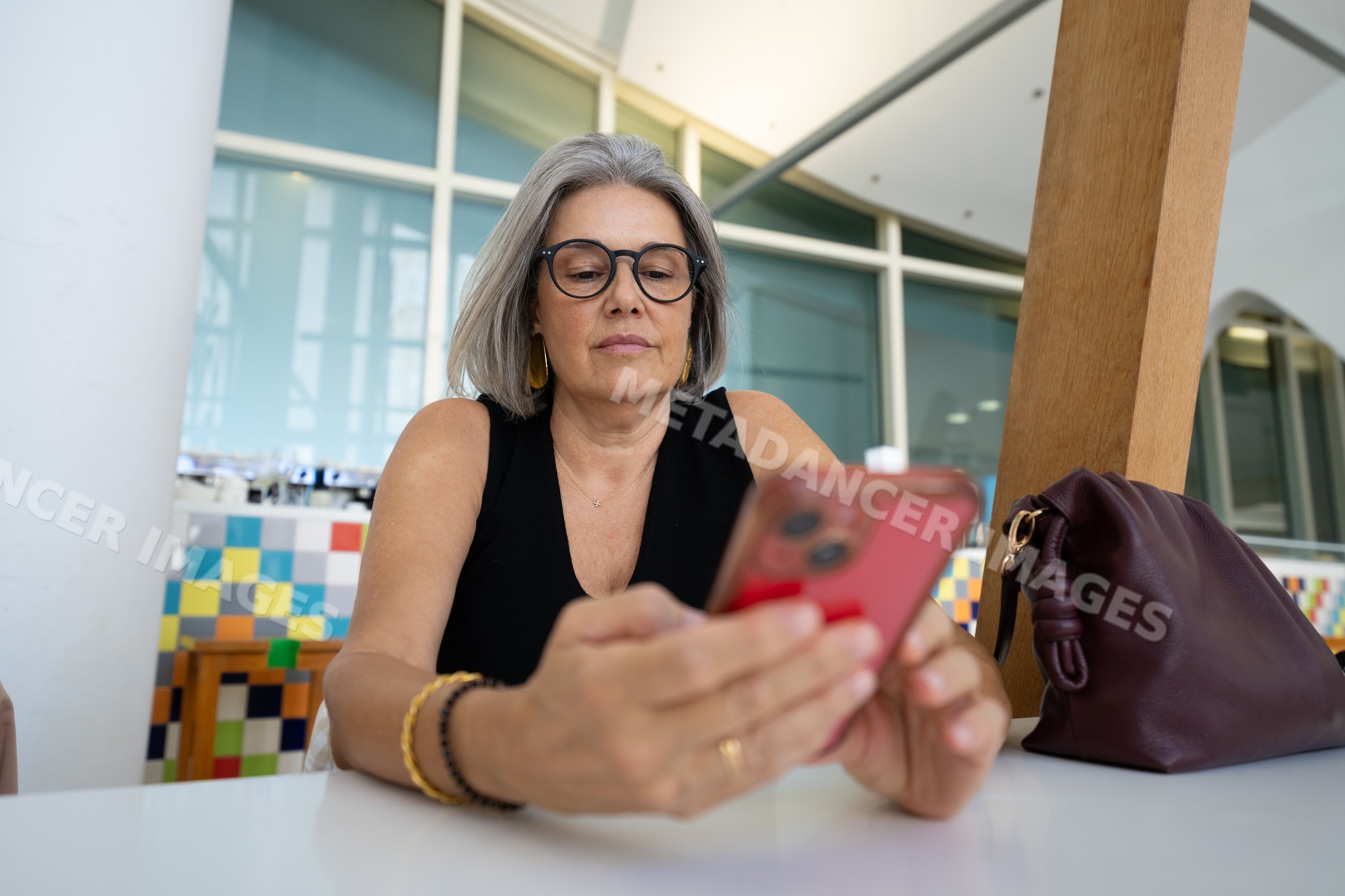 White woman with glasses using smartphone at indoor modern location
