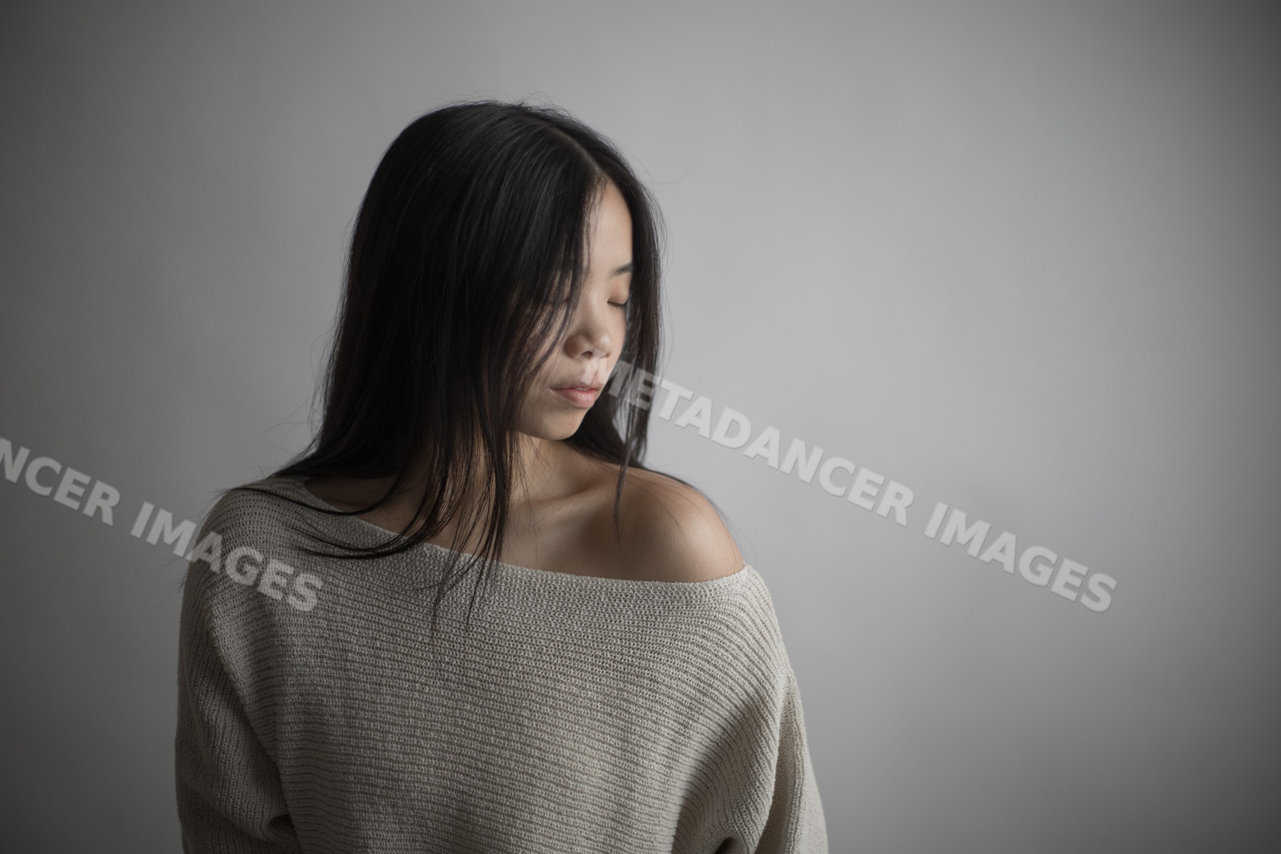 Southeast Asian woman in knitted off-shoulder sweater with serene